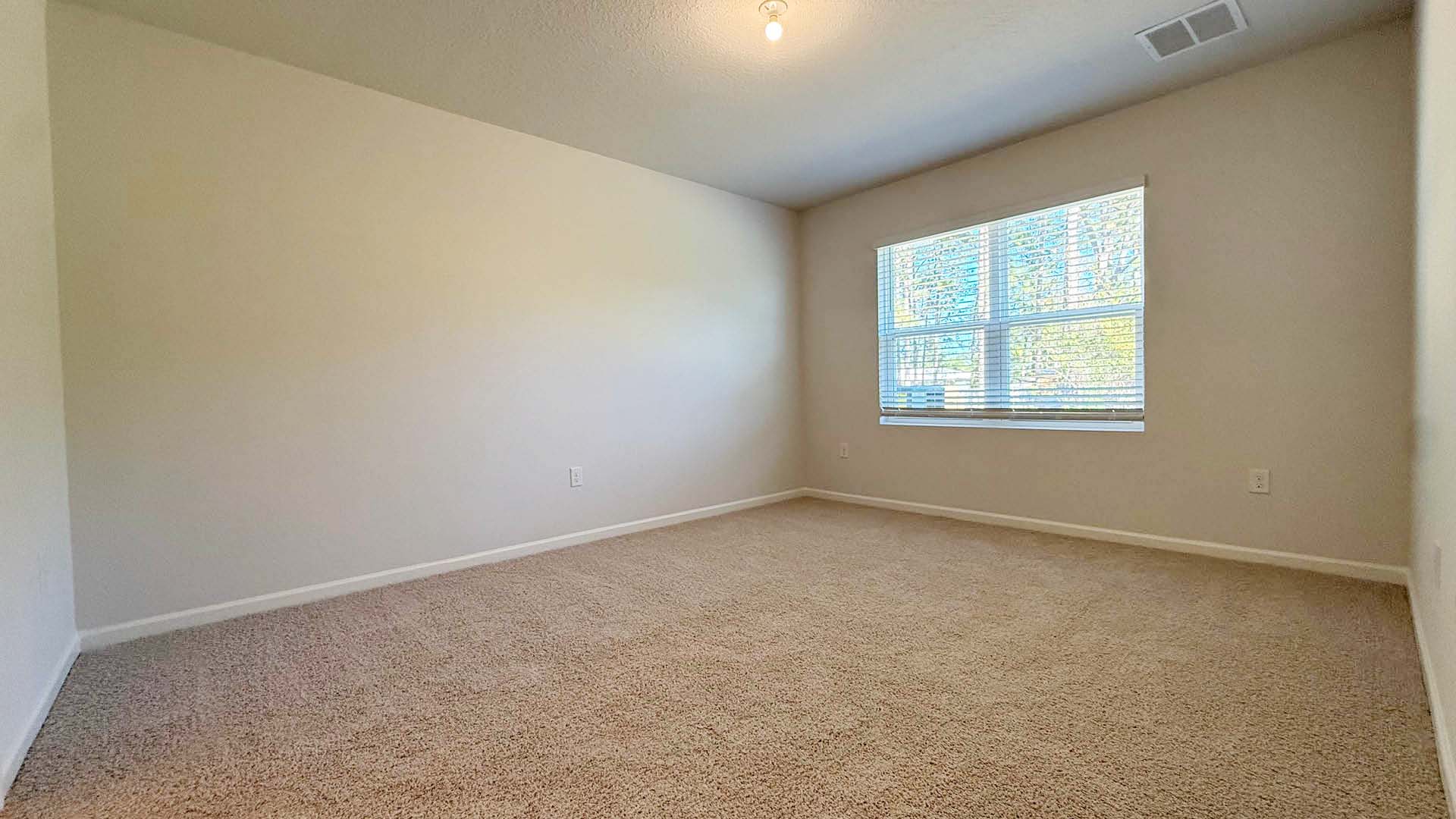 Empty room with carpeted floor and a window allowing natural light to enter.