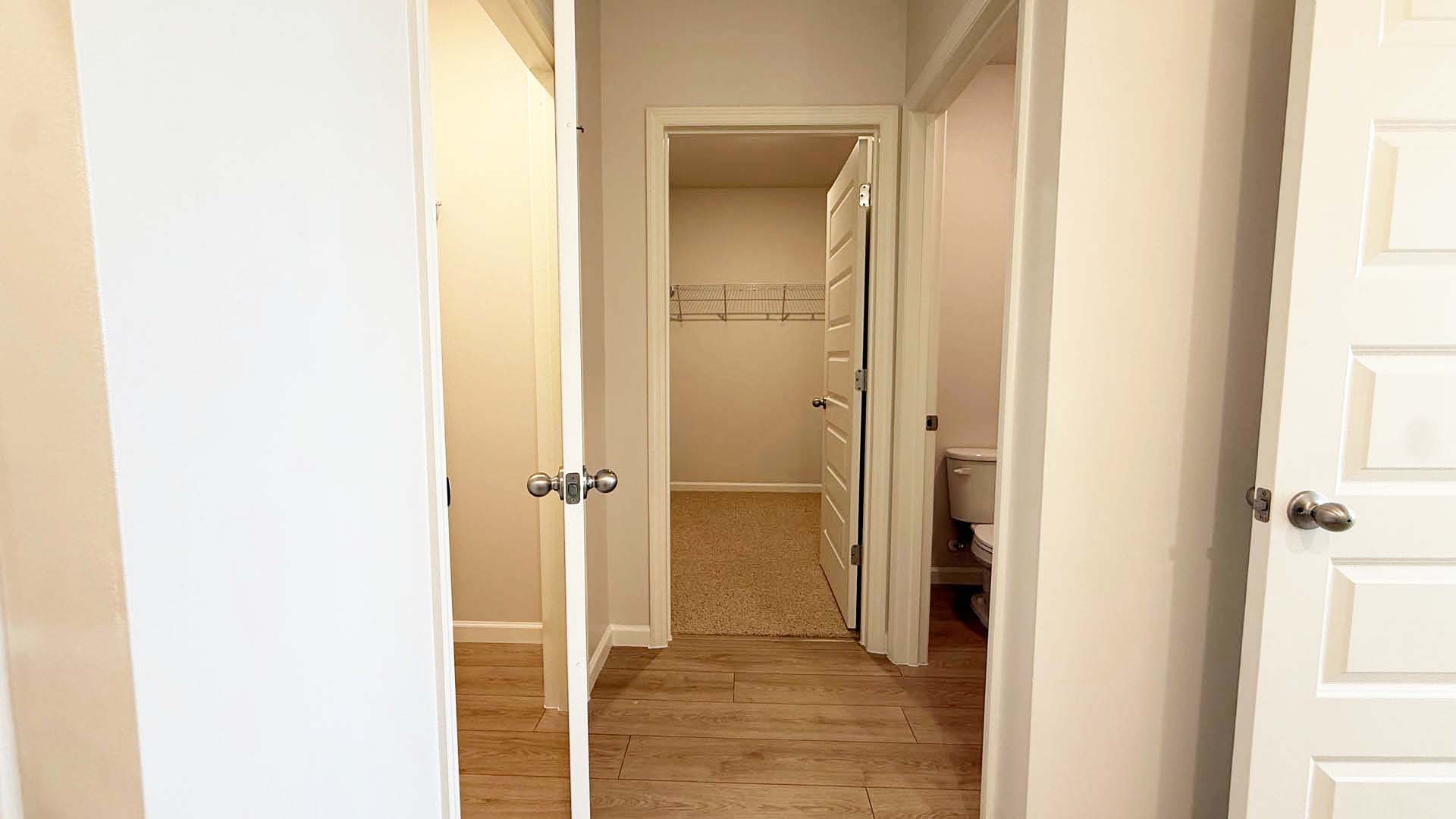 A hallway featuring a door and a toilet, providing a glimpse of a functional restroom area.
