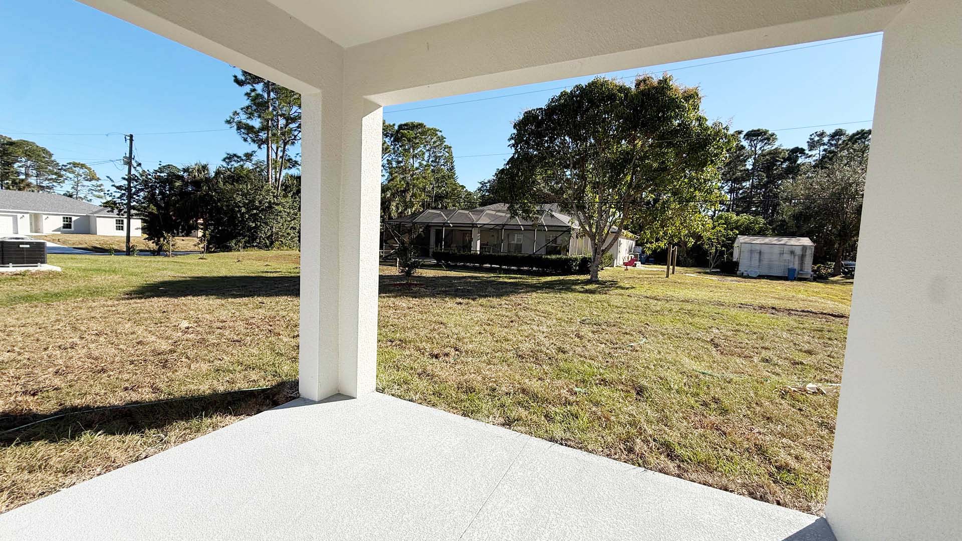 A view of a lush backyard from an open porch, showcasing greenery and a serene outdoor space.