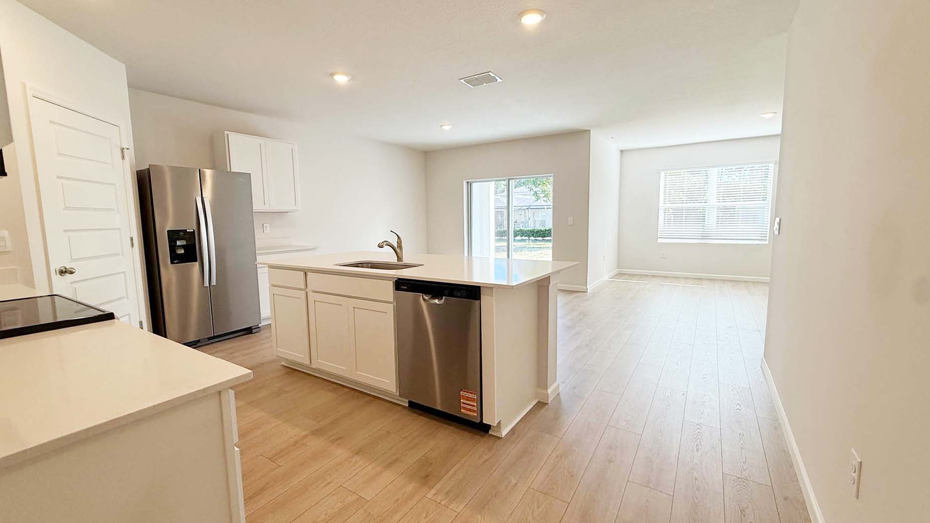 A modern kitchen featuring stainless steel appliances and elegant plank floors.