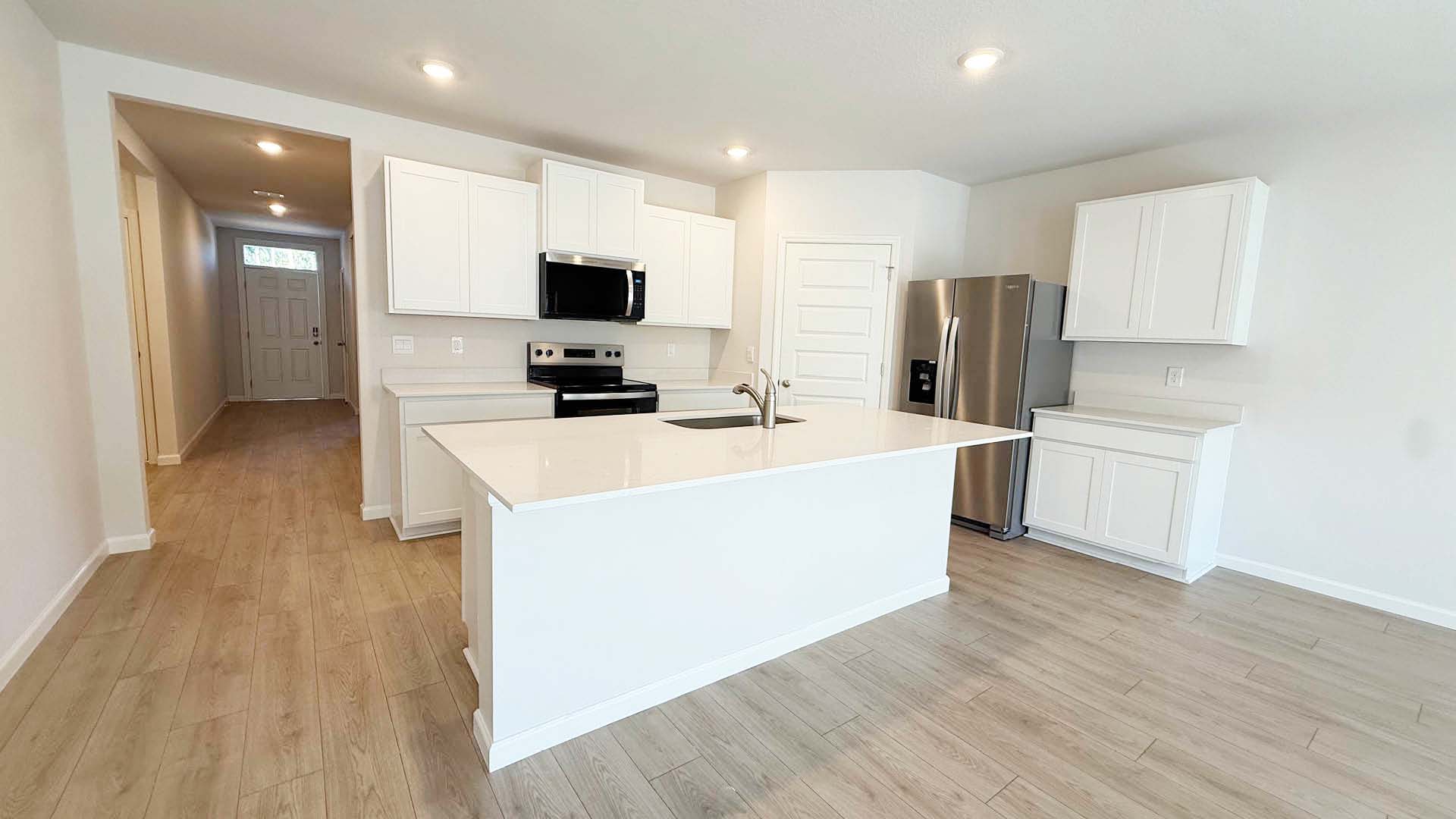A bright white kitchen featuring white cabinets and warm plank floors, creating a clean and inviting atmosphere.