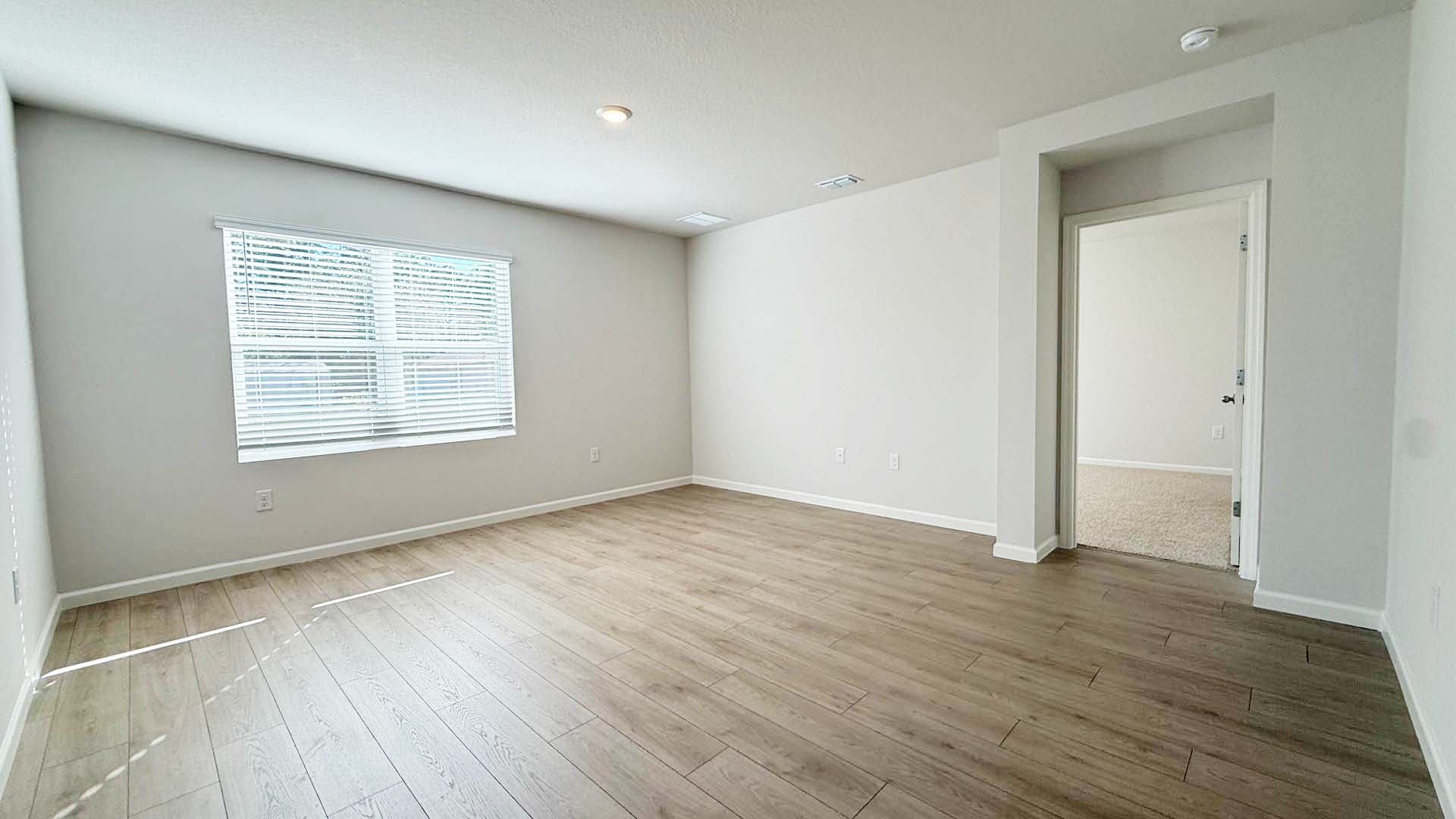 Empty room featuring plank floors and white walls, creating a bright and spacious atmosphere.