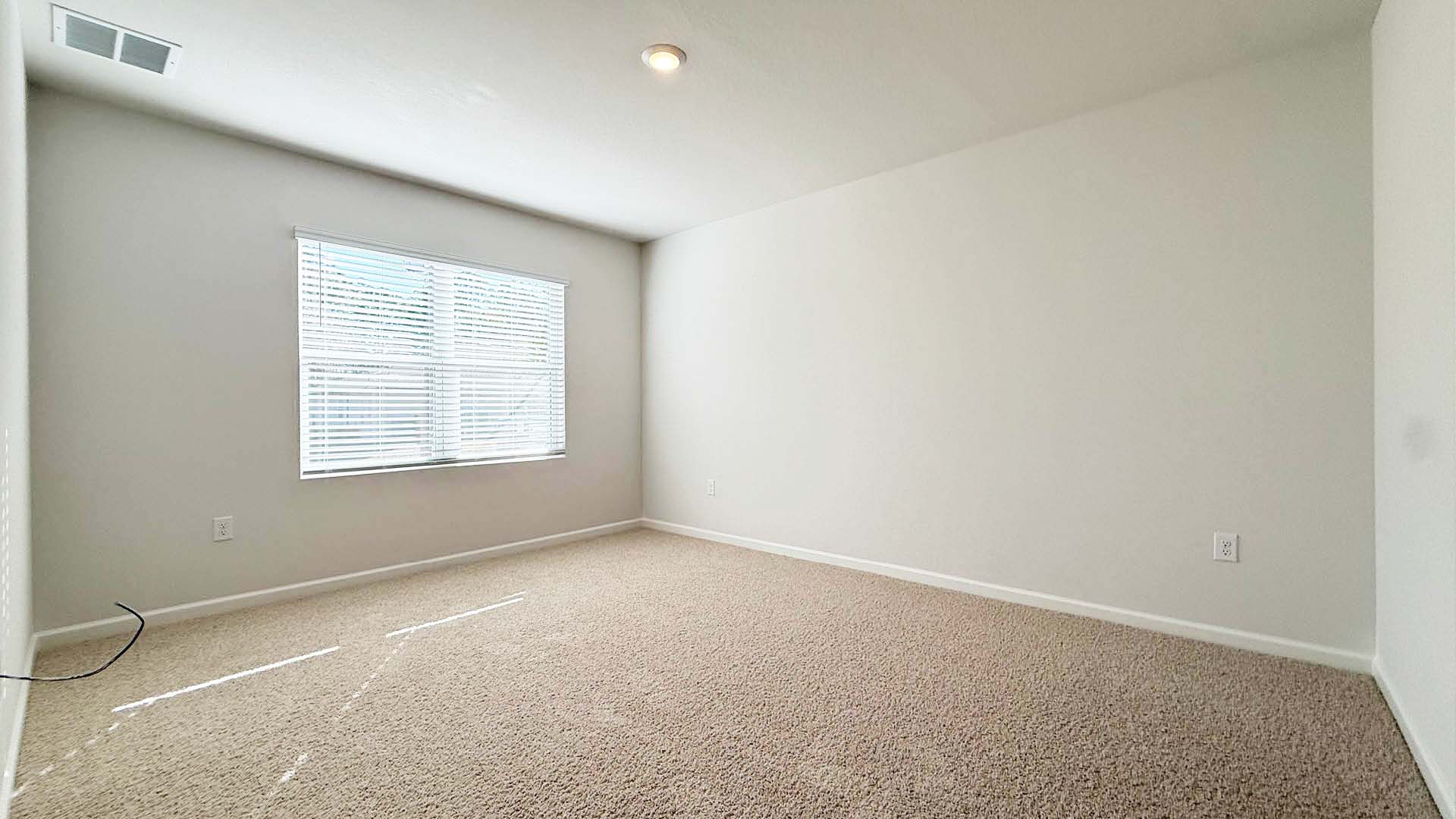 Empty room with carpeted floor and a window allowing natural light to enter.