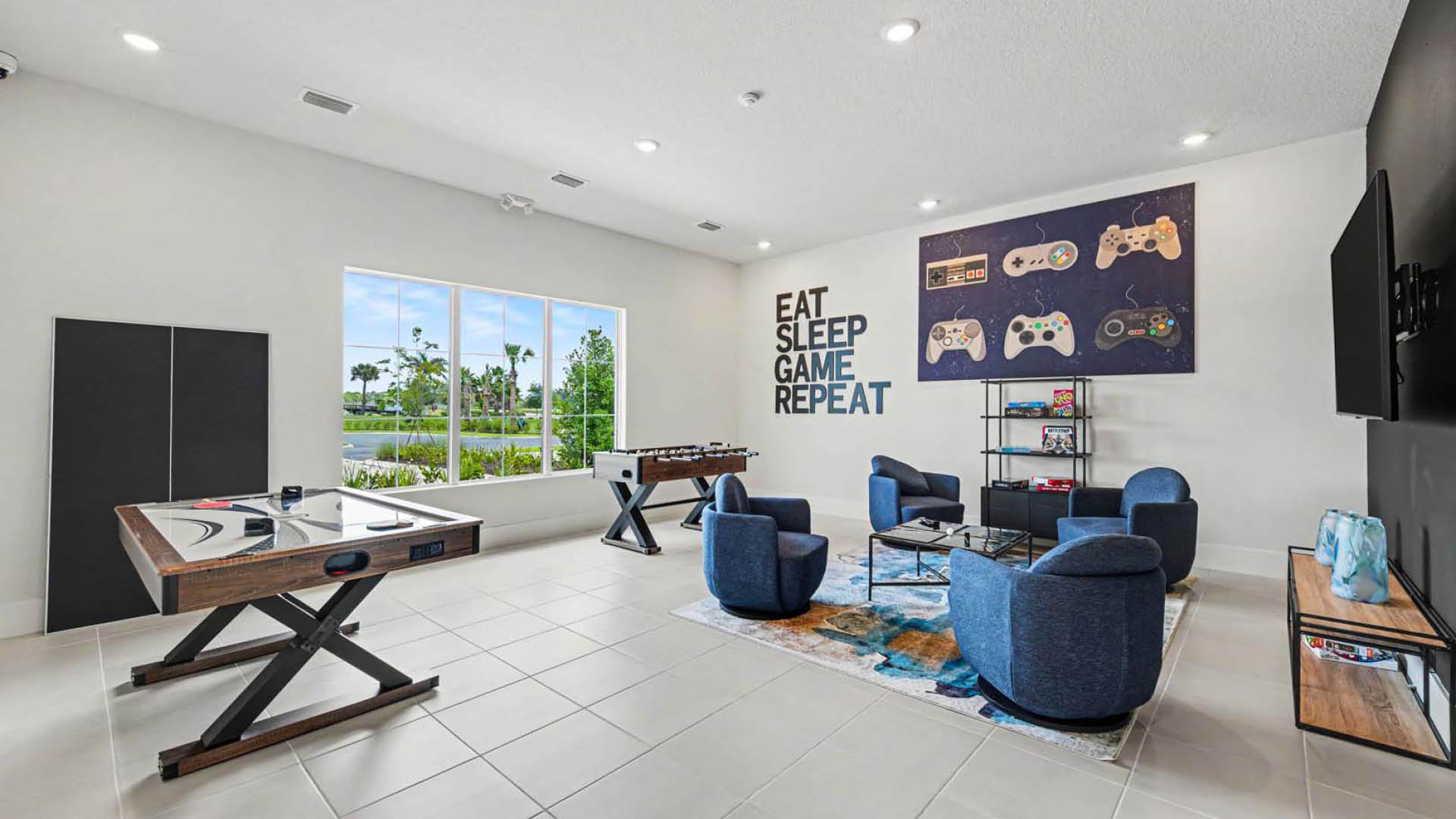 A game room with a TV, a multi-use gaming table, a foosball table, seating, and board games.