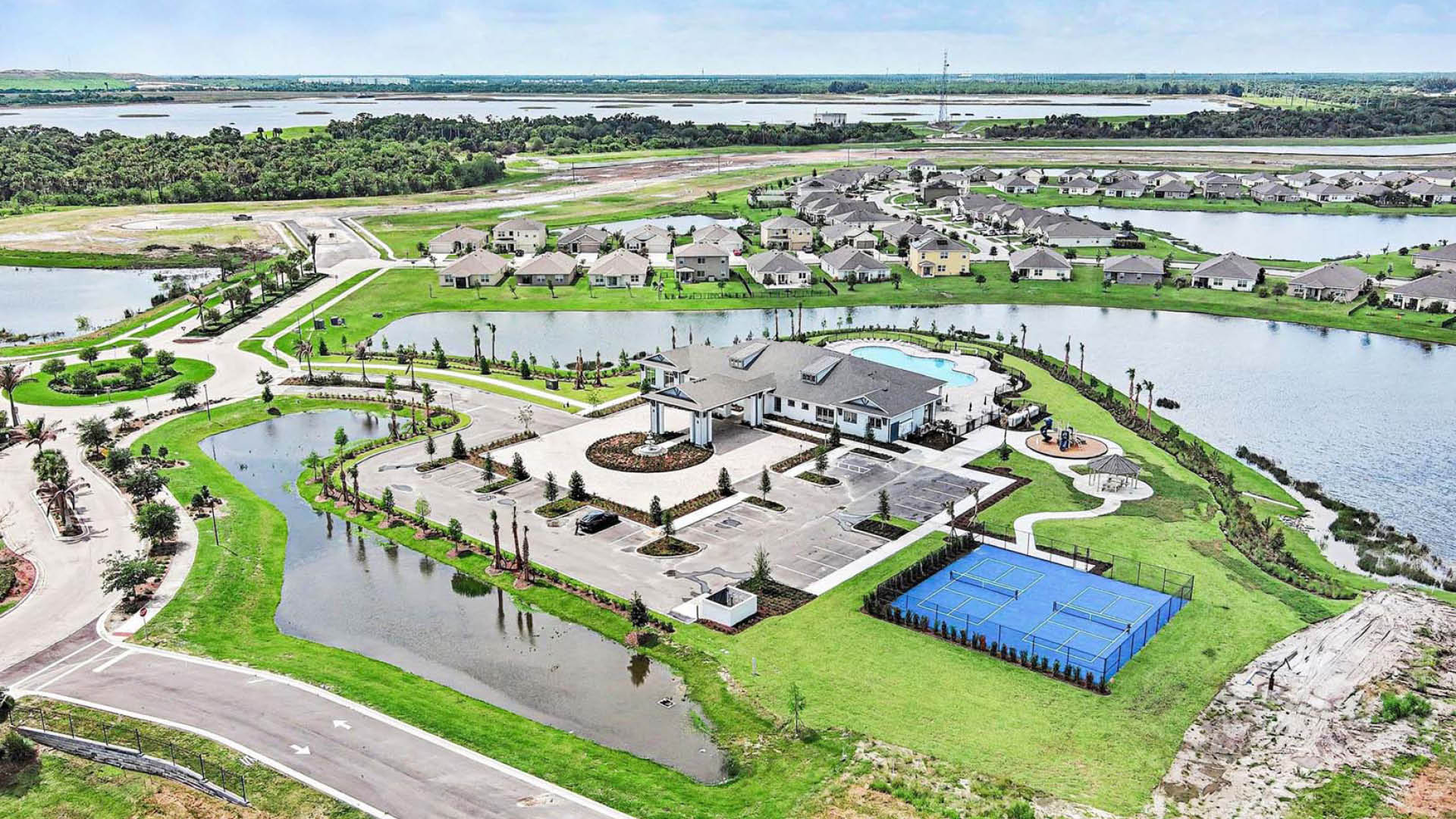 An aerial view of the resort-style amenities, inlcuding the pickleball court, pool, playground, and large community clubhouse.