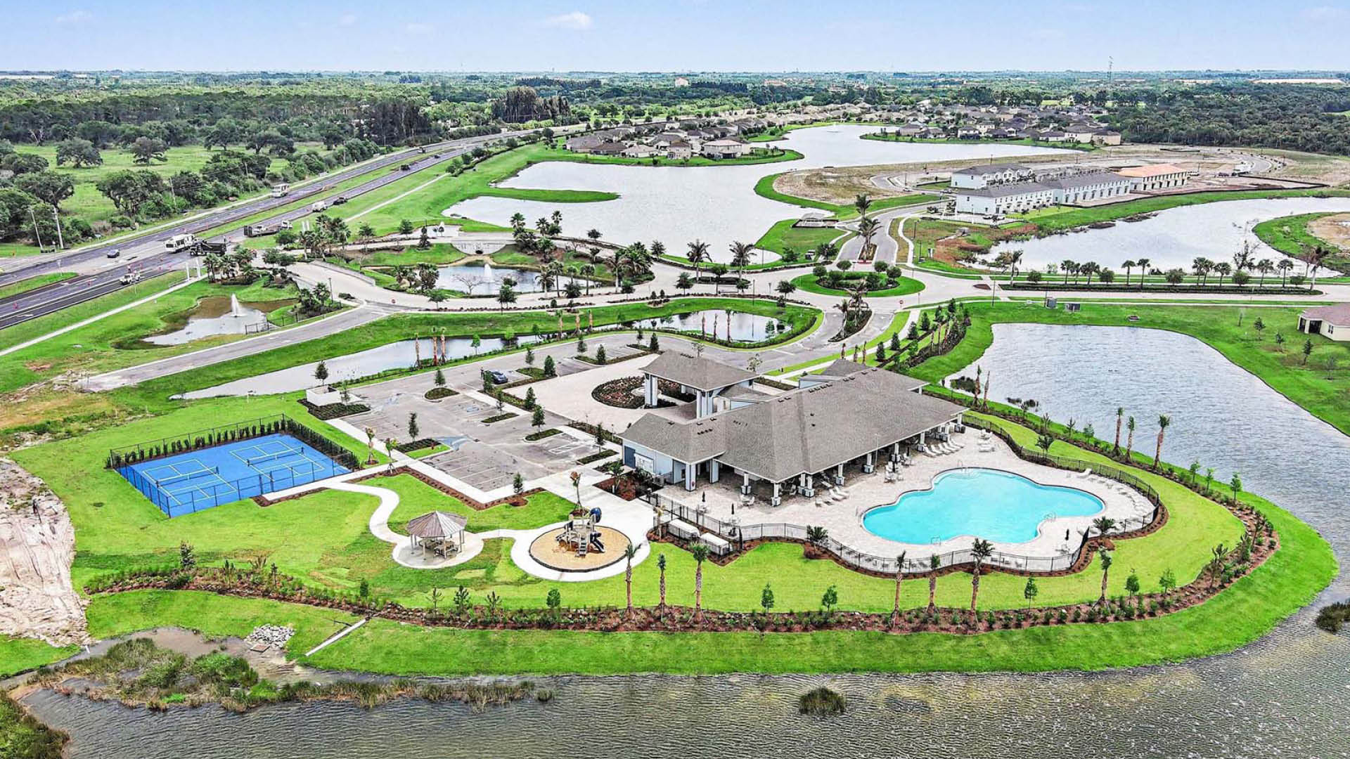 An aerial view of the resort-style amenities, inlcuding the pickleball court, pool, playground, and large community clubhouse.