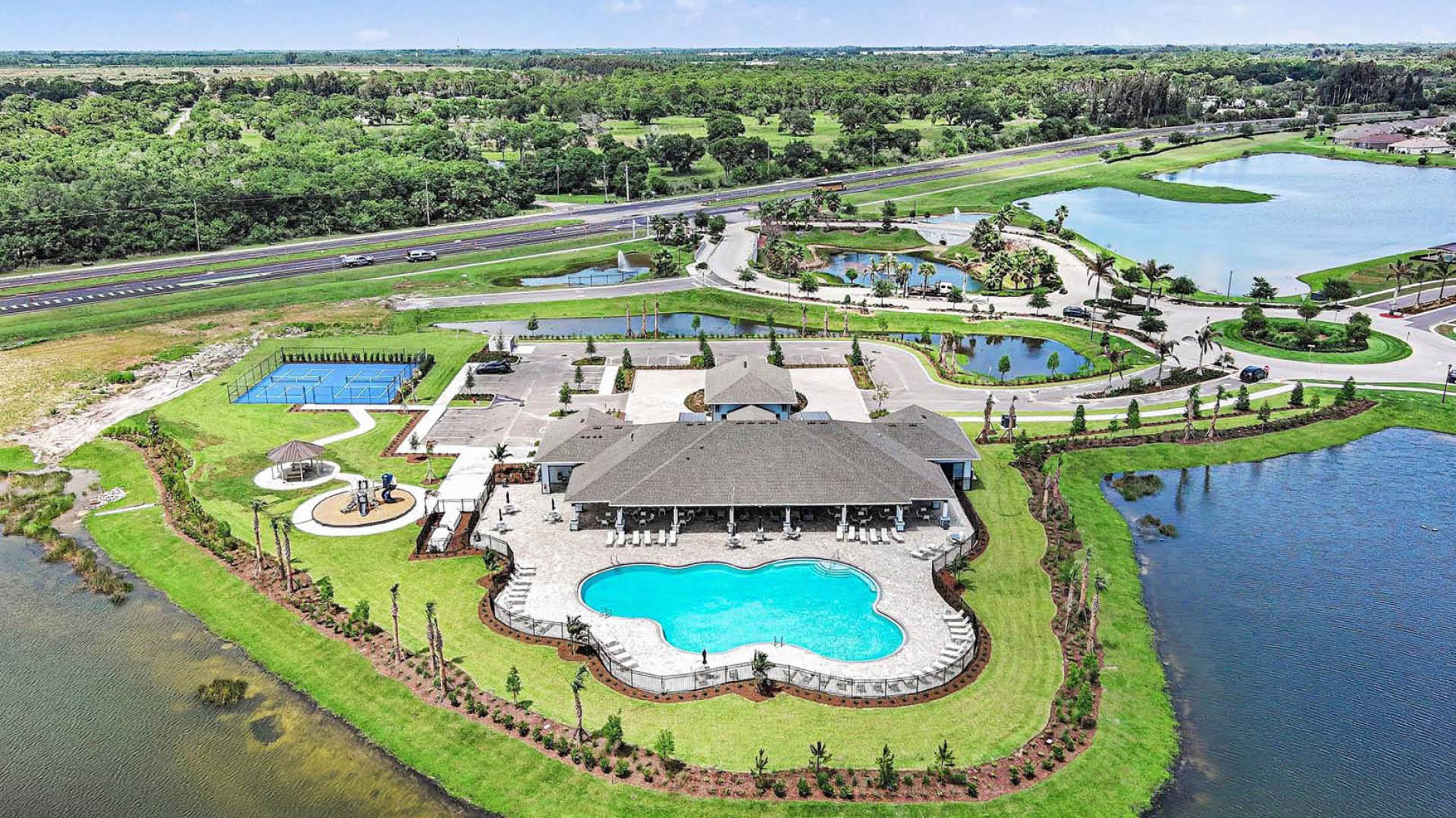 An aerial view of the resort-style amenities, inlcuding the pickleball court, pool, playground, and large community clubhouse.