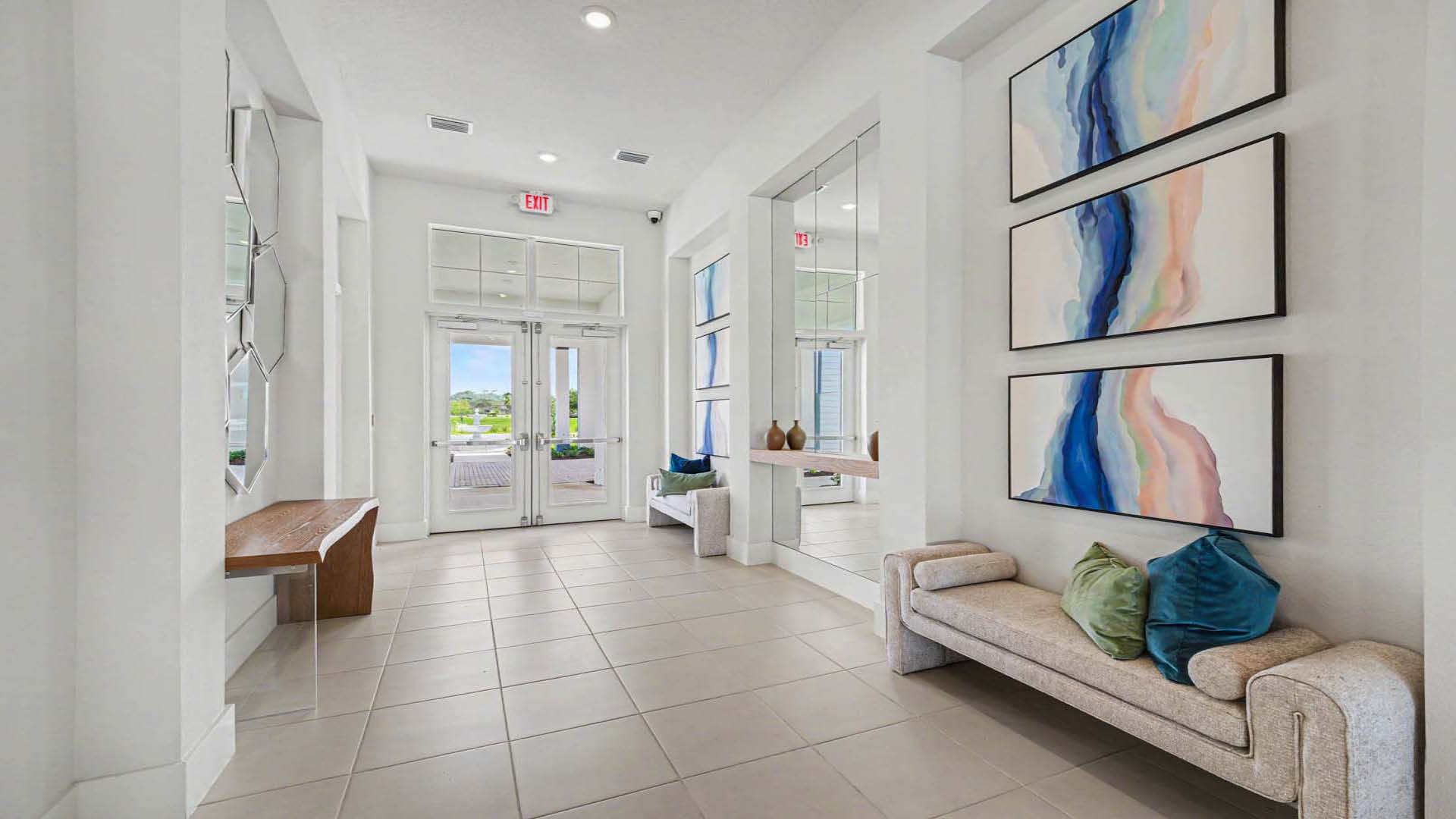 A bright and vibrant entry with benches, artwork, and mirrors.