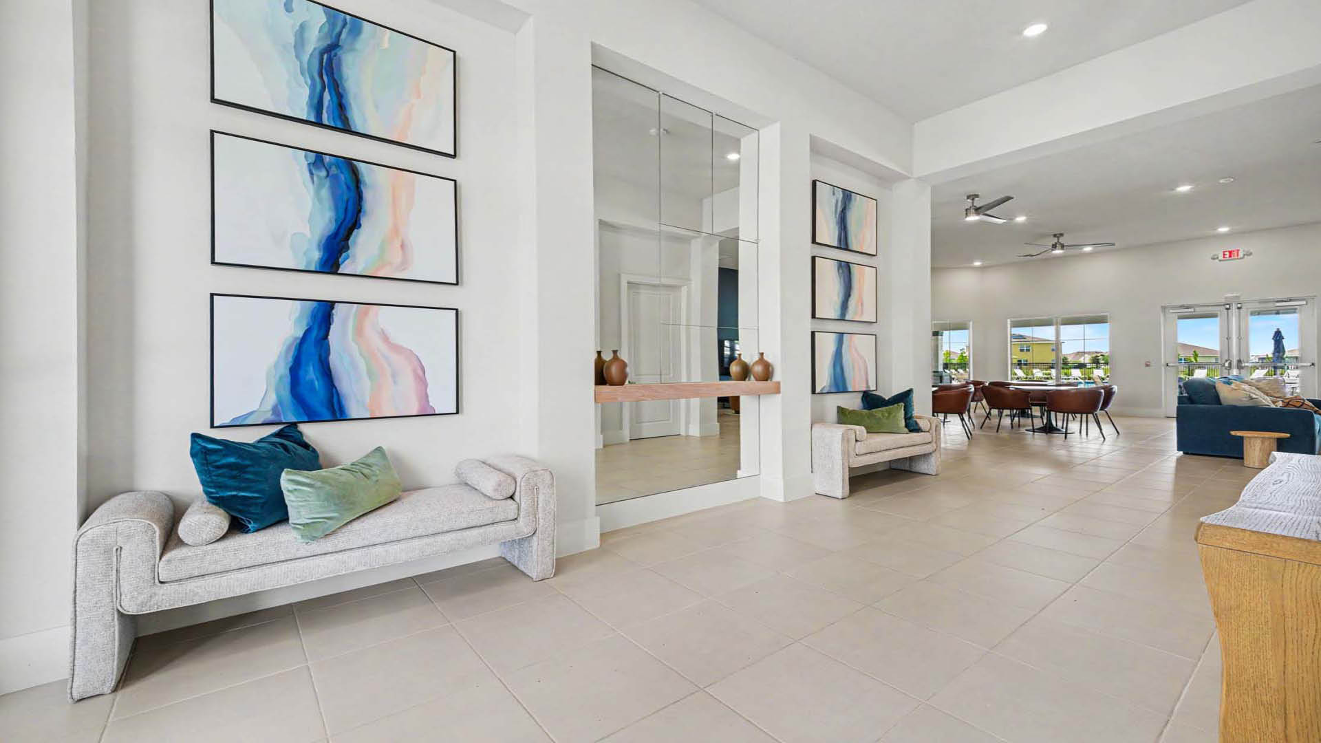 A bright and vibrant entry with benches, artwork, and mirrors. A large gathering area with many tables and seating arrangements is visible.
