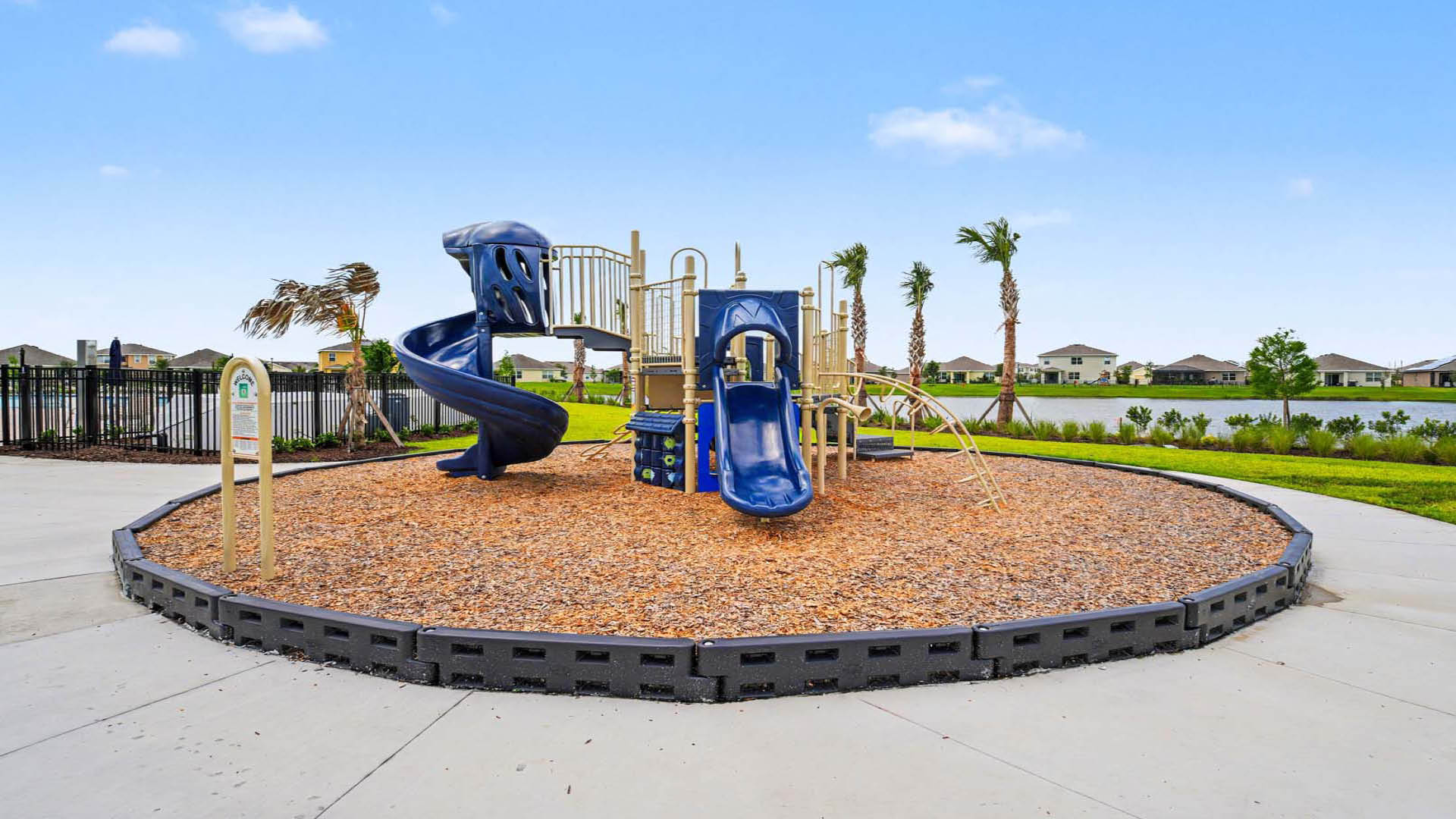 An outdoor playground with a large climbing and playing area with slides. A gorgeous lake view is in the background..