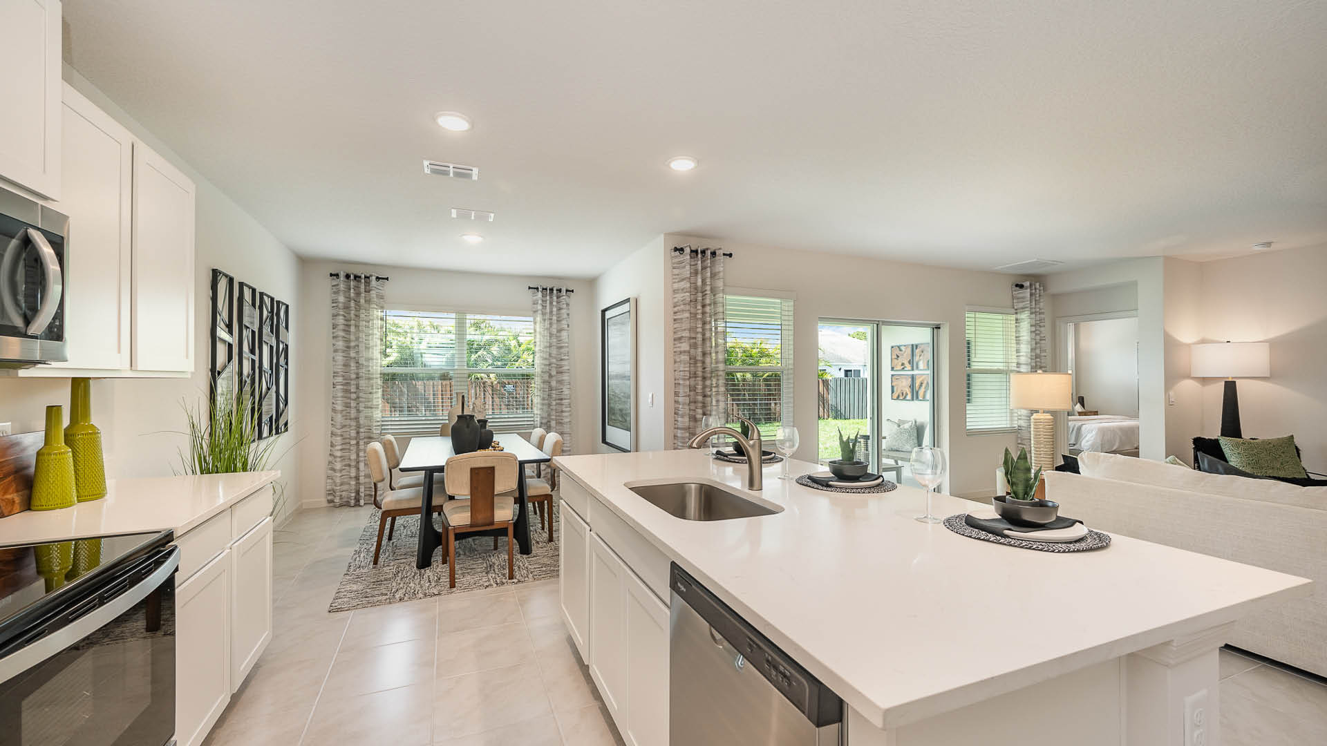 Bright, open living area with tile flooring, modern kitchen, and sliding doors leading to a patio; neutral walls enhance spaciousness.
