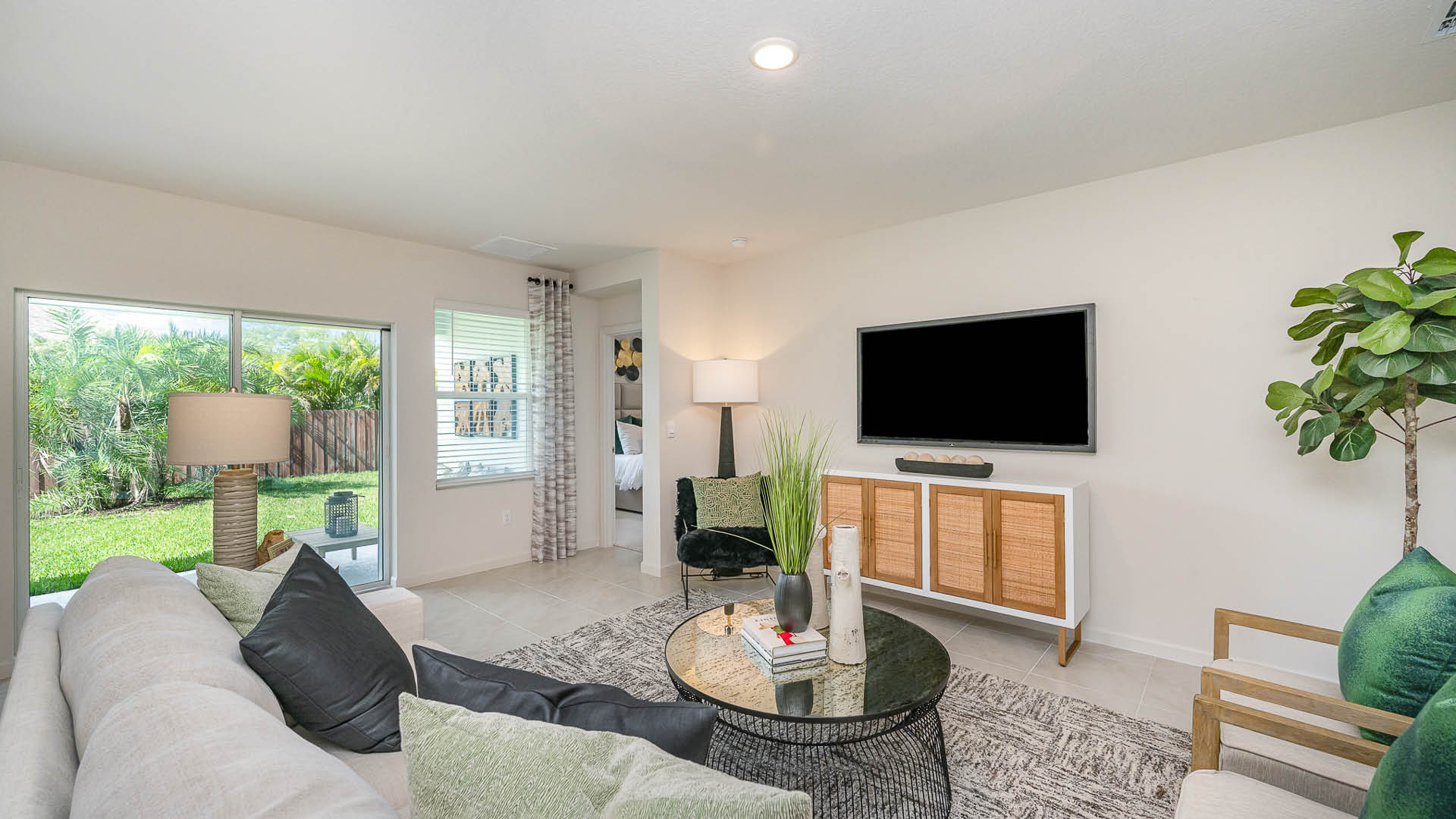 Bright, open living area with tile flooring, modern kitchen, and sliding doors leading to a patio; neutral walls enhance spaciousness.