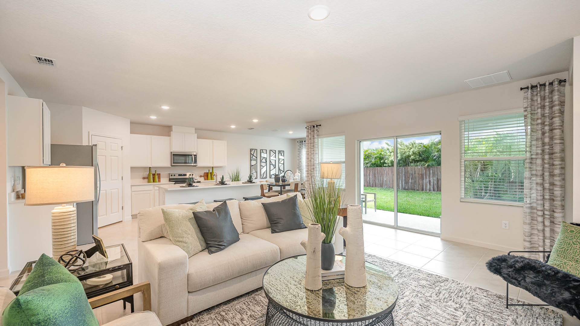 Bright, open living area with tile flooring, modern kitchen, and sliding doors leading to a patio; neutral walls enhance spaciousness.