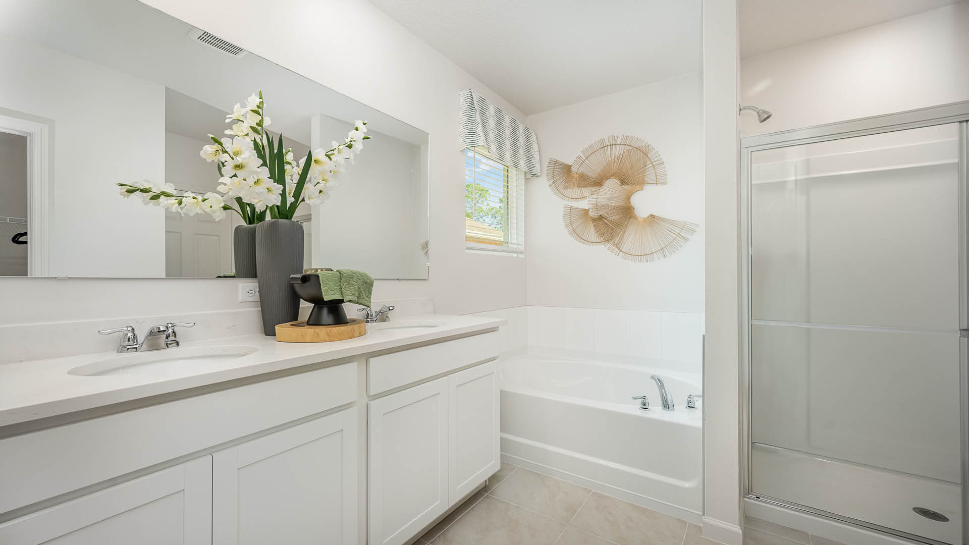 Bright and modern bathroom featuring a double vanity, soaking tub, large mirror, and decorative plants against a light, airy backdrop.