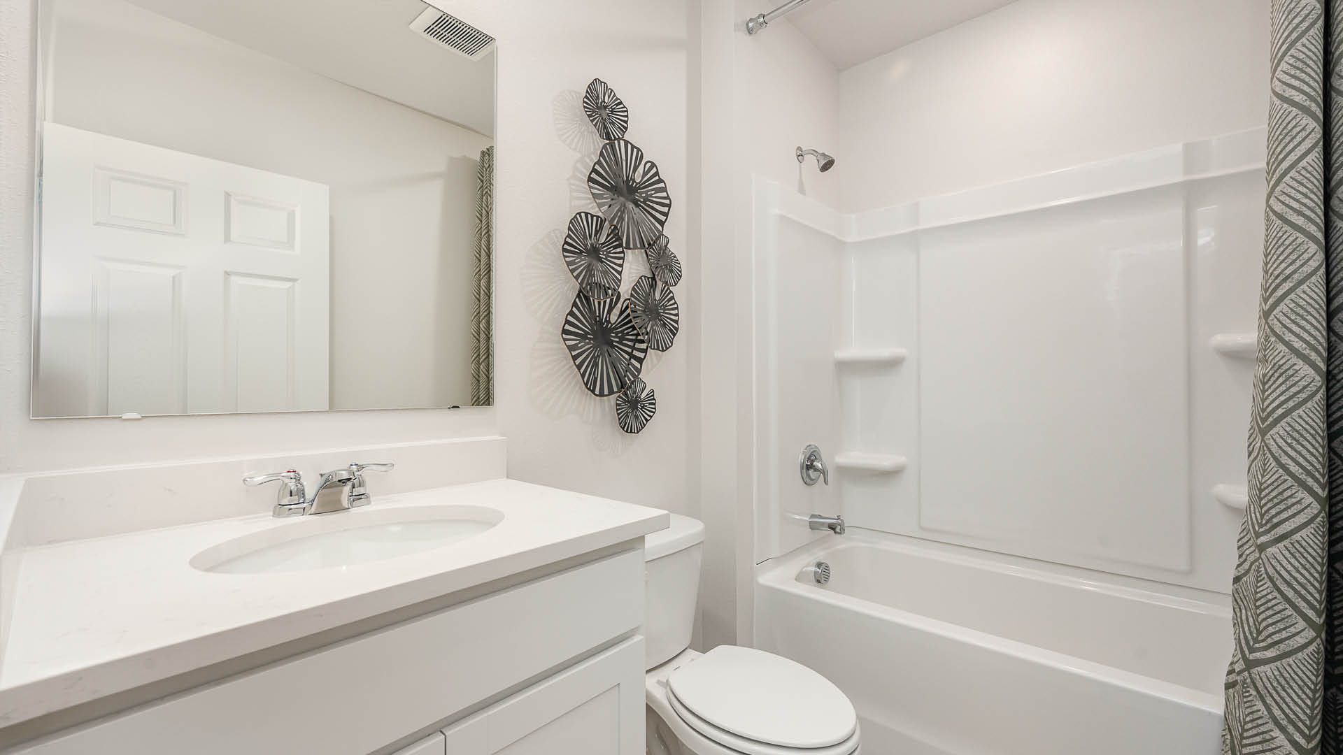 Modern bathroom featuring a white vanity, round mirror, and patterned shower curtain, adorned with decorative wall art.