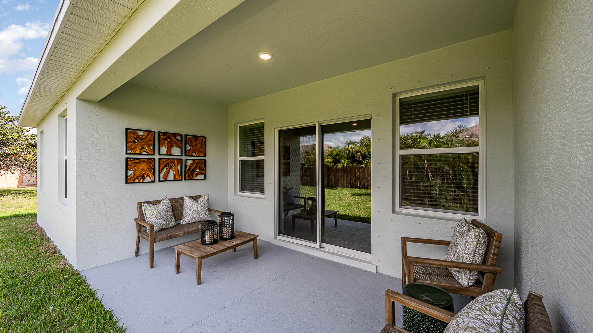 Cozy patio featuring a comfortable seating area with decorative pillows, a wooden coffee table, and nature-inspired artwork on the wall.