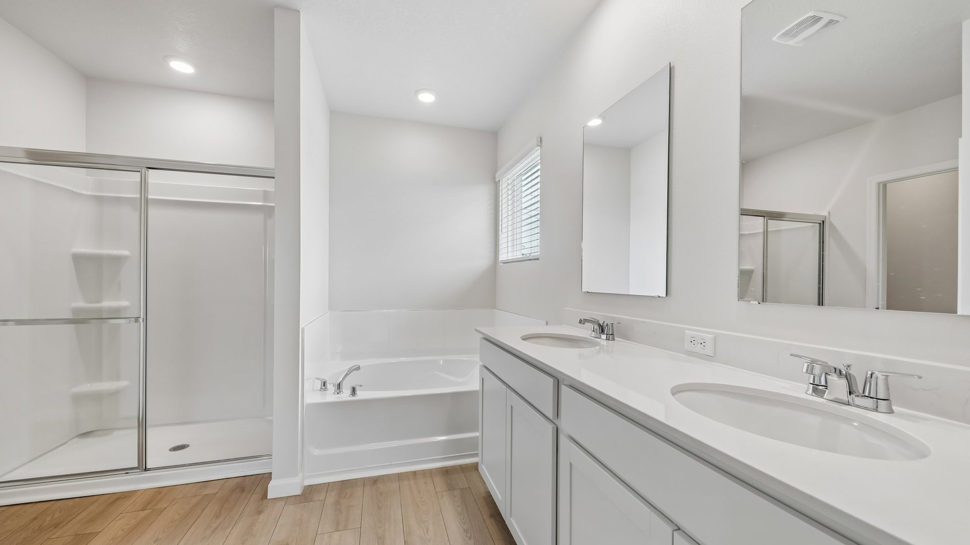 A spacious, ensuite bathroom featuring a double sink vanity with quartz countertops, a walk-in shower, and a large separate tub.