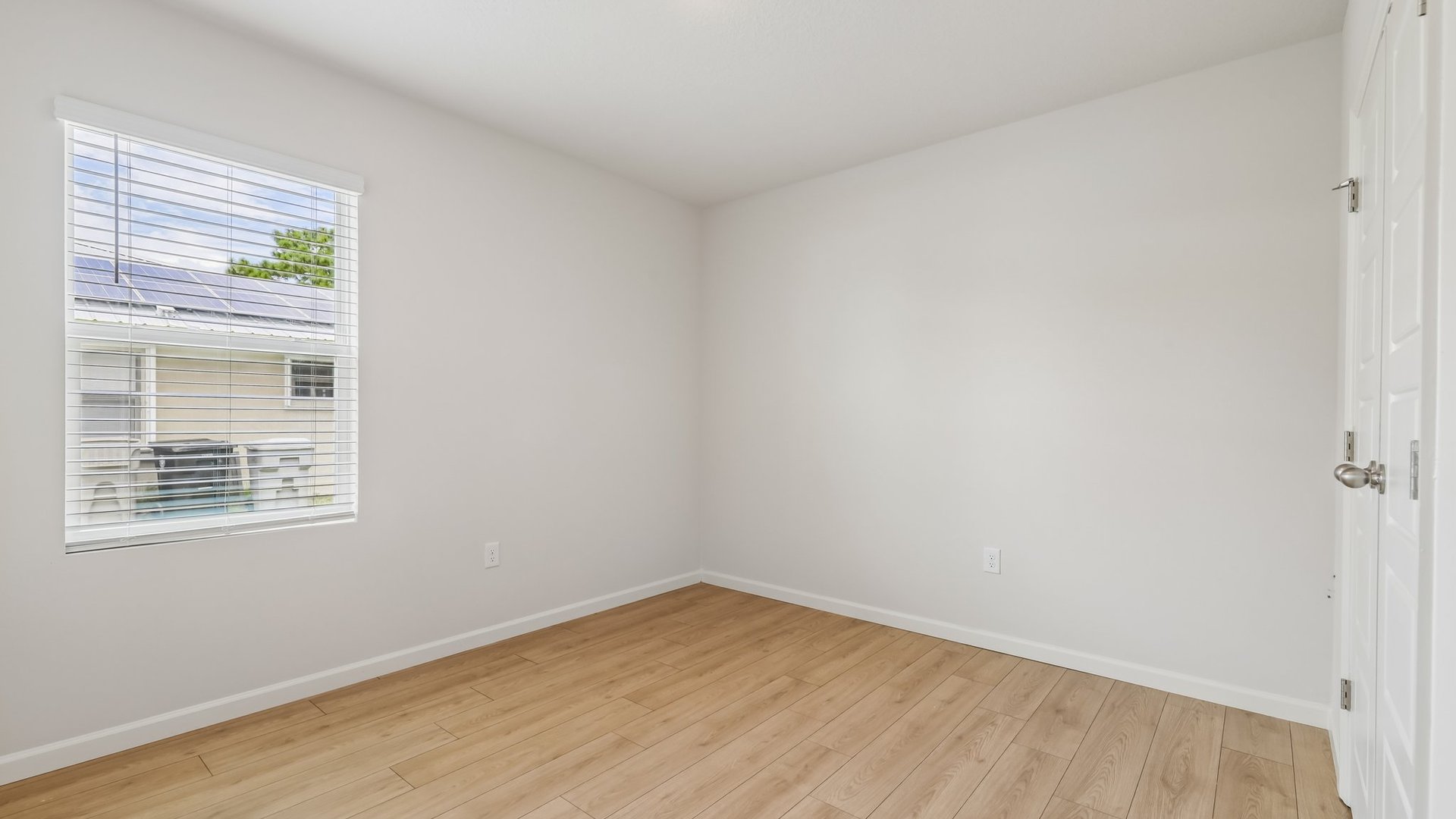 An empty room with a window and double door closet.