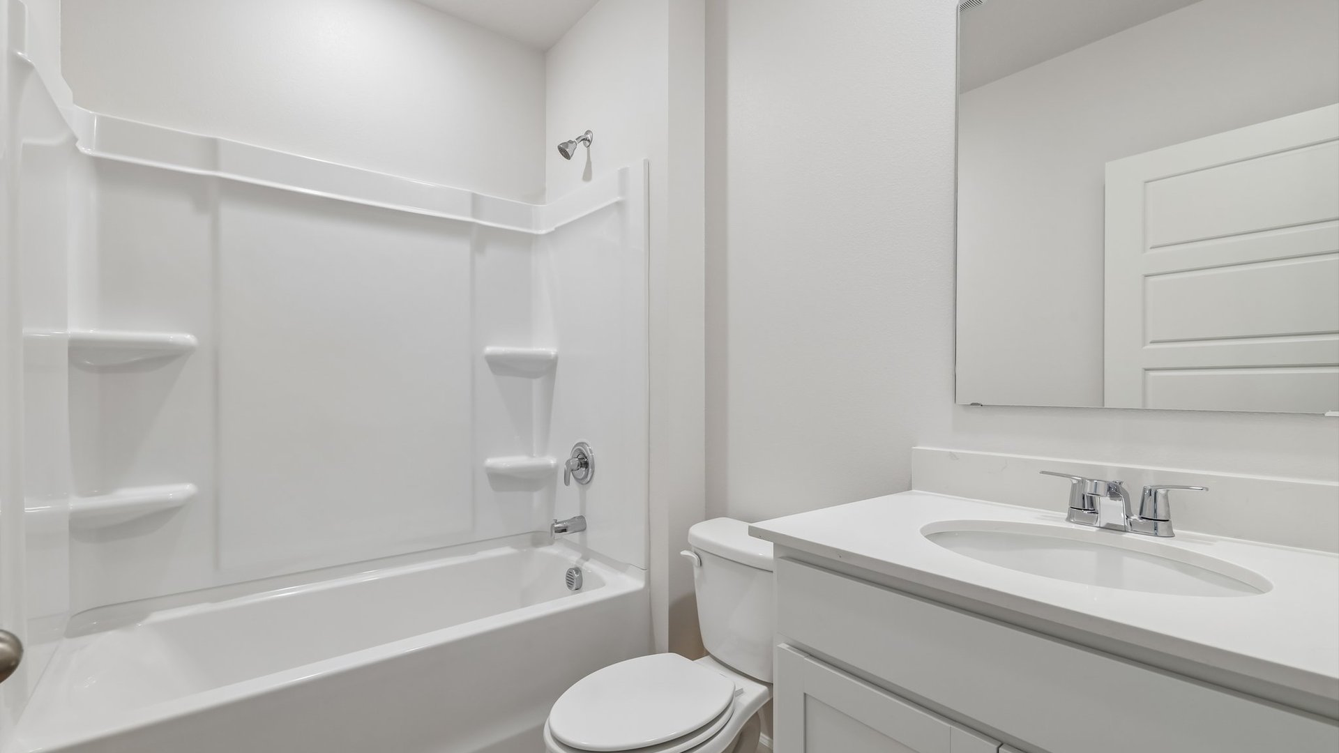 A clean, modern bathroom featuring quartz countertops, a bathtub with a shower, and a large mirror against neutral-colored walls.