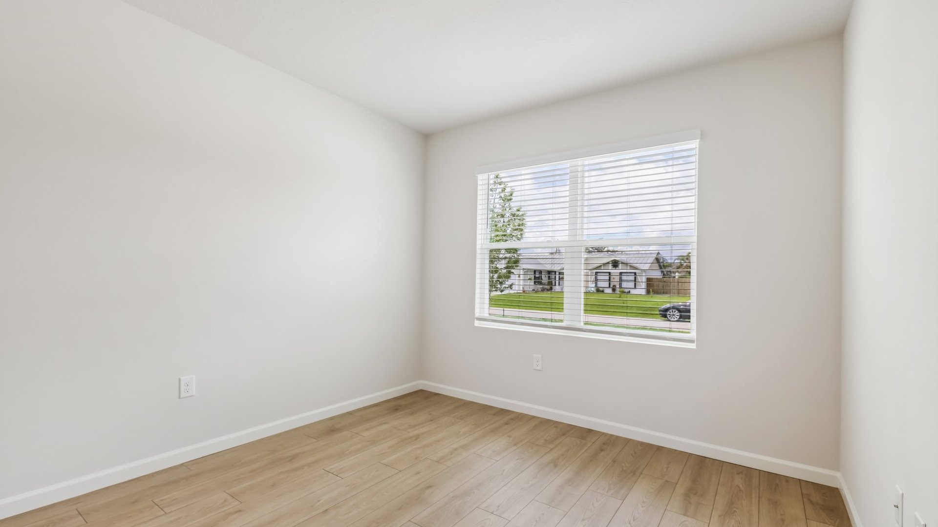 An empty room with a large window, allowing natural light to illuminate the space.
