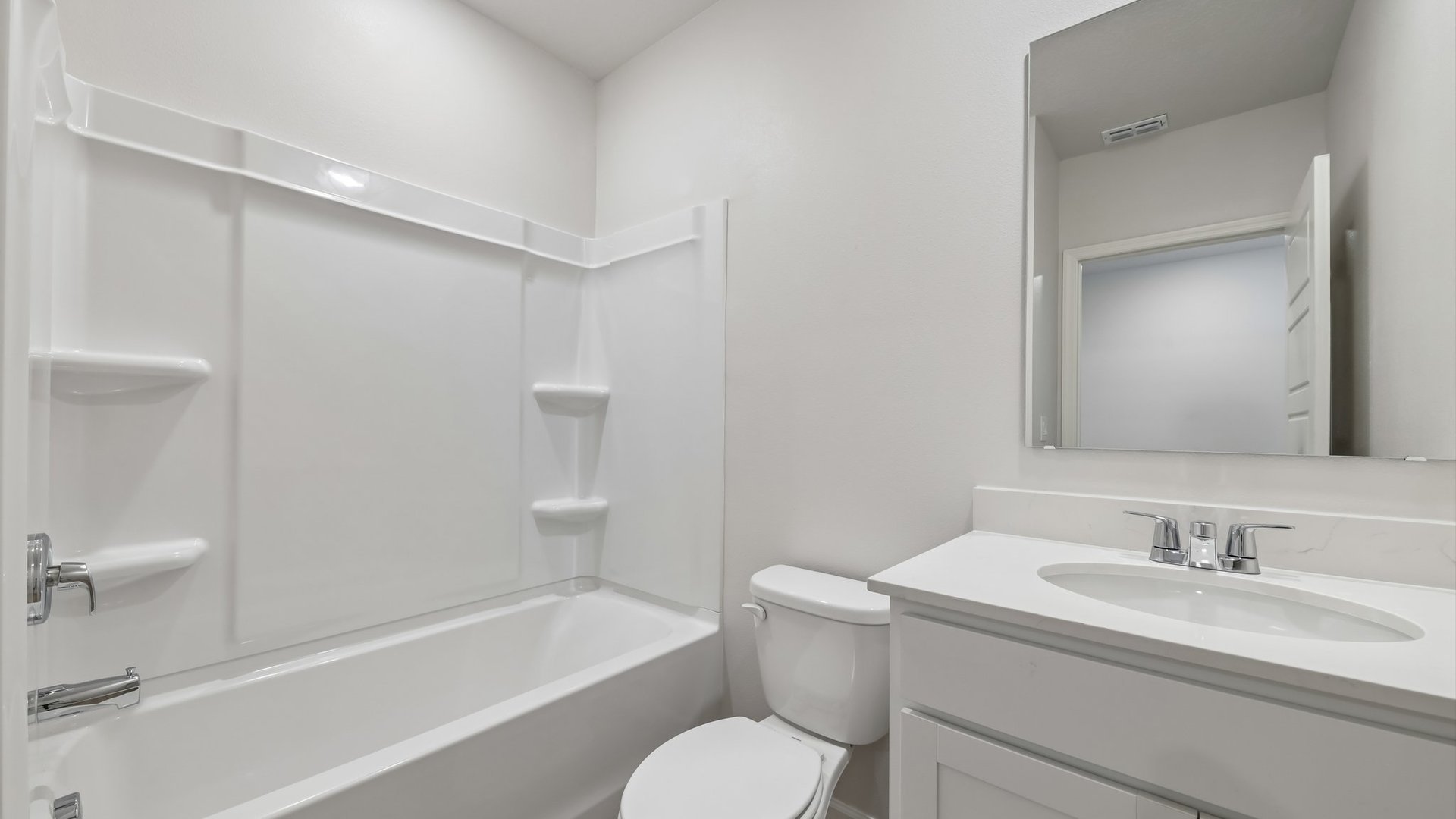 A clean, modern bathroom featuring quartz countertops, a bathtub with a shower, and a large mirror against neutral-colored walls.