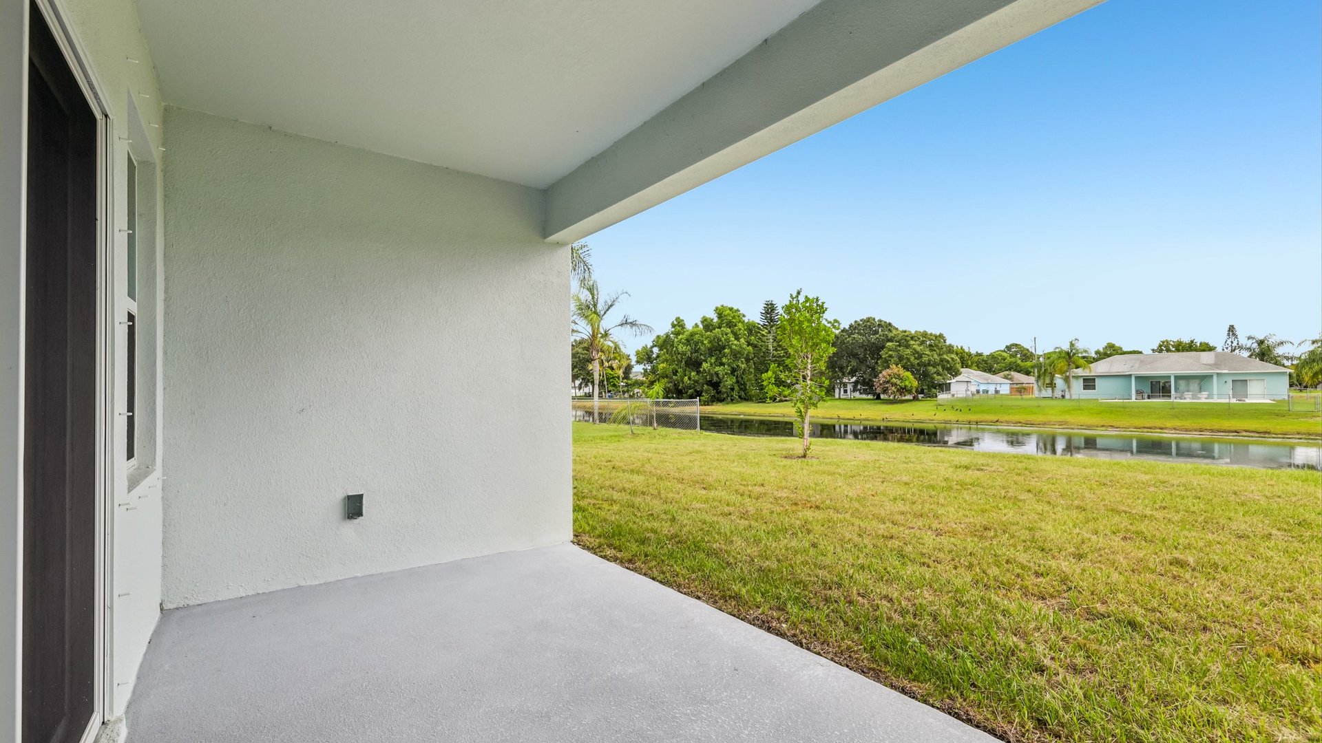 A rear view of a house featuring a stucco exterior, sliding glass door, and a covered patio.