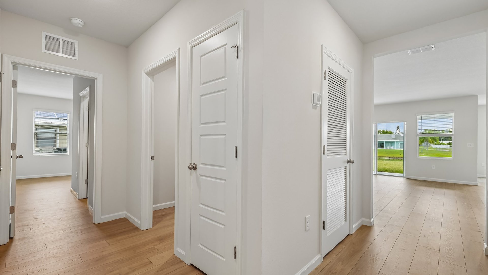 A bright entryway hallway with an open door to a laundry room and several doors leading elsewhere.