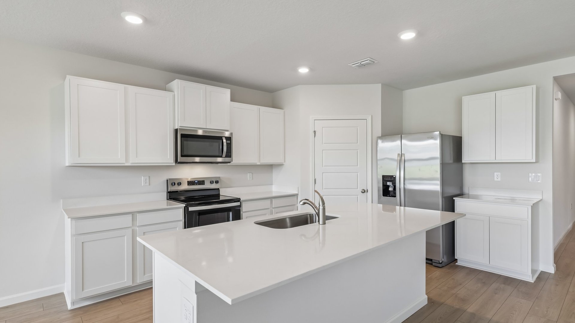 A large kitchen and dining area with quartz countertops, stainless steel appliances, and an island with room for seating.