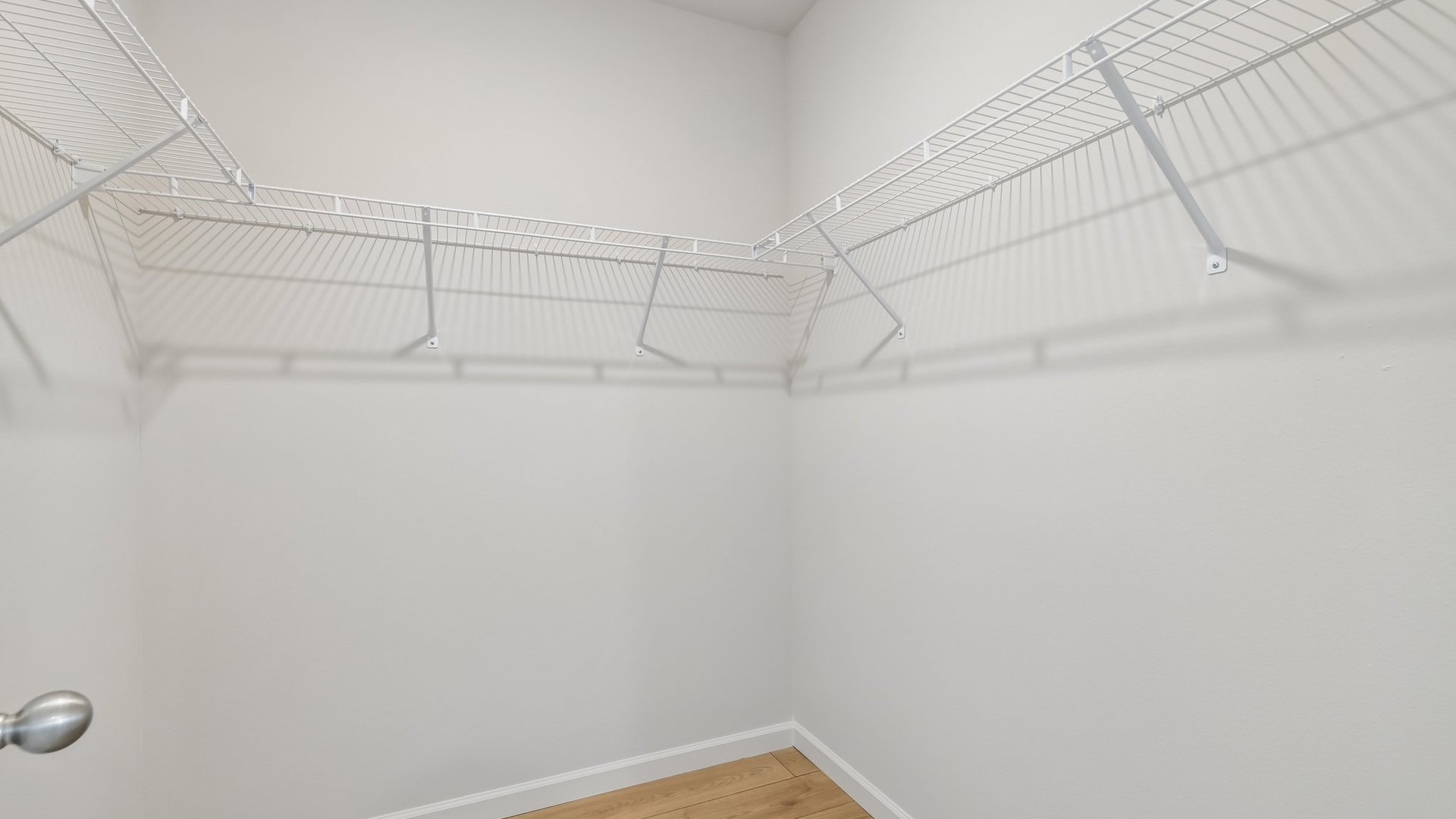A spacious, walk-in closet with white wire shelves.