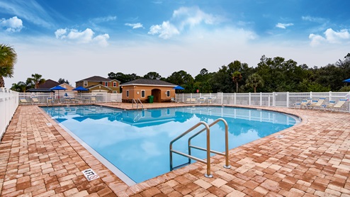 Resort-Style Pool with paver deck, lounge chairs and bathrooms.