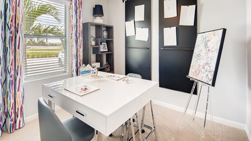 Flex Room with large window, beige carpet, decorated as an office.