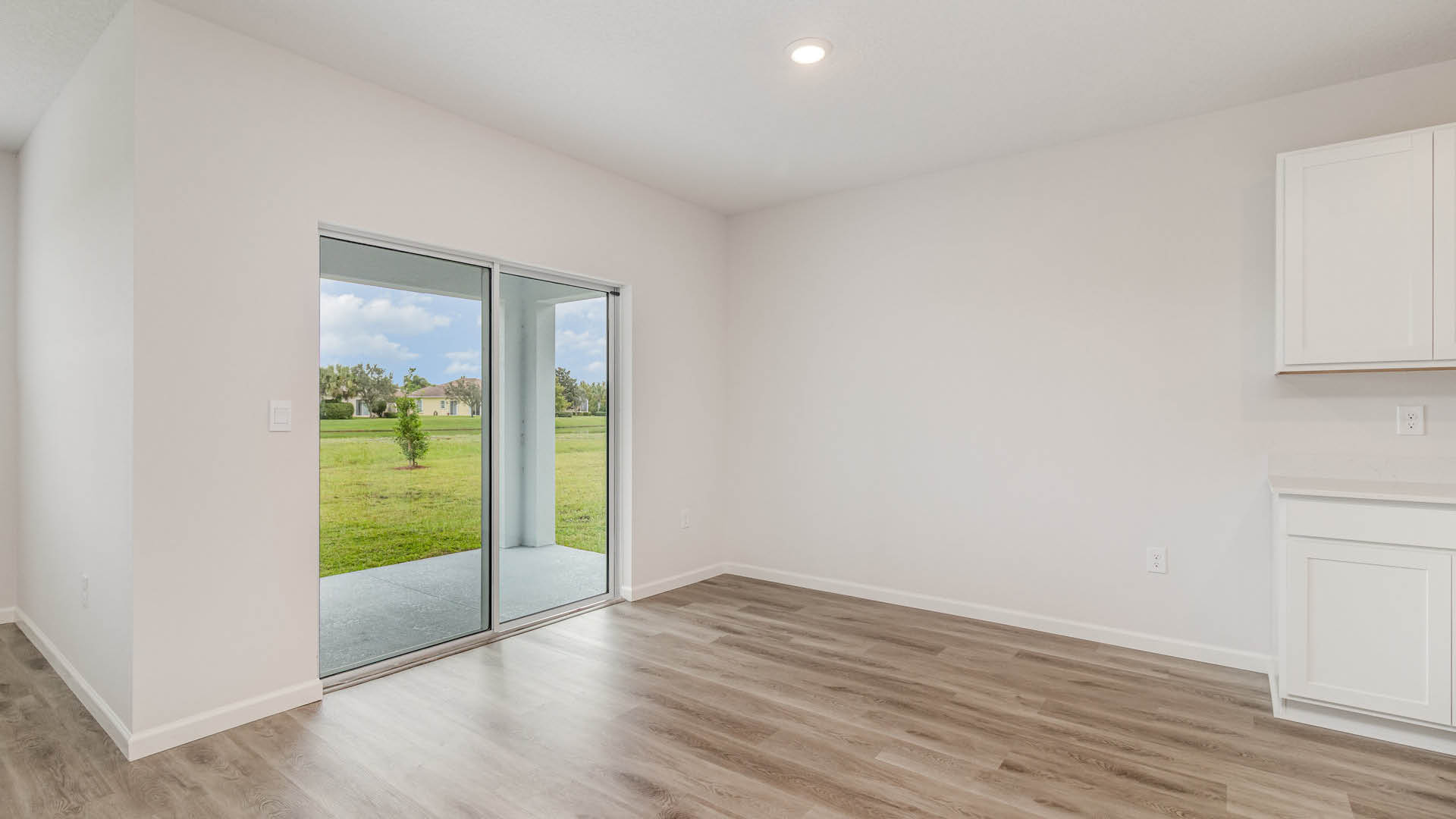 Bright, empty dining area featuring sliding glass doors opening to a green outdoor area.