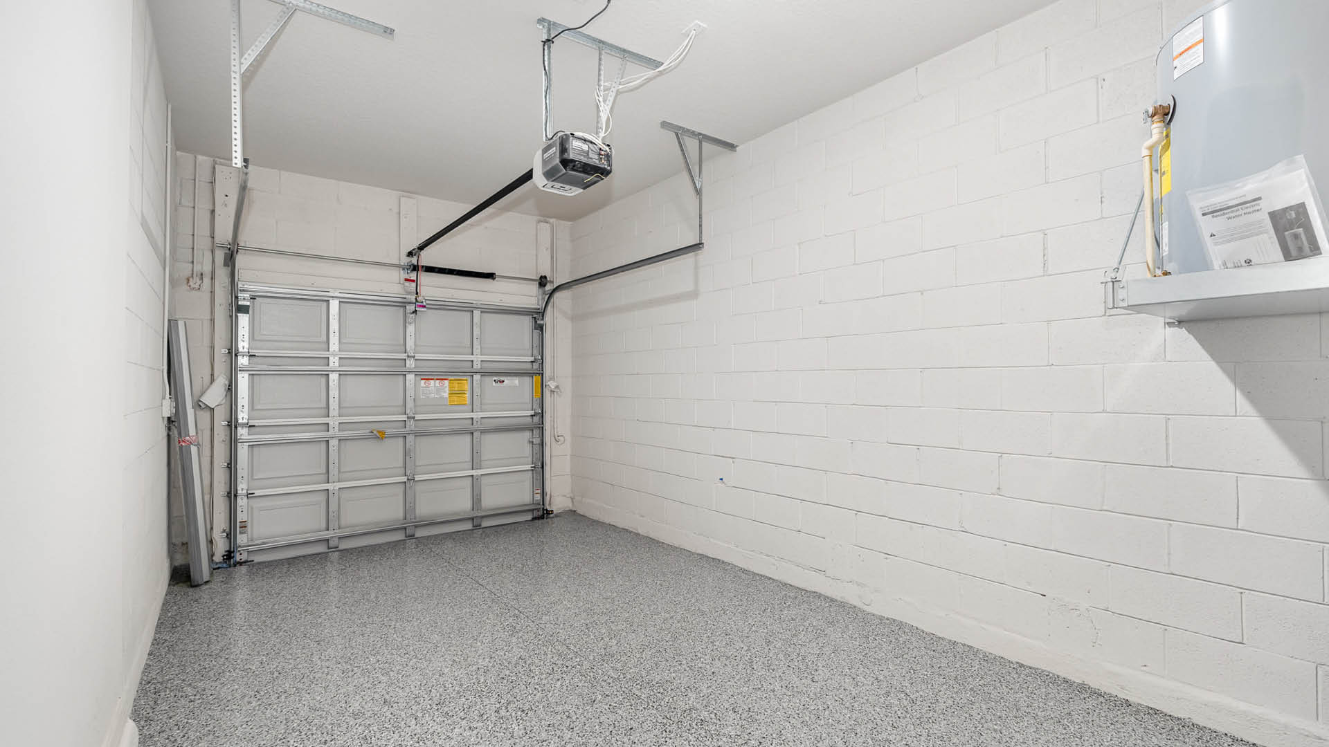 A spacious, 1-car garage with a garage door, and a white cinder block wall.