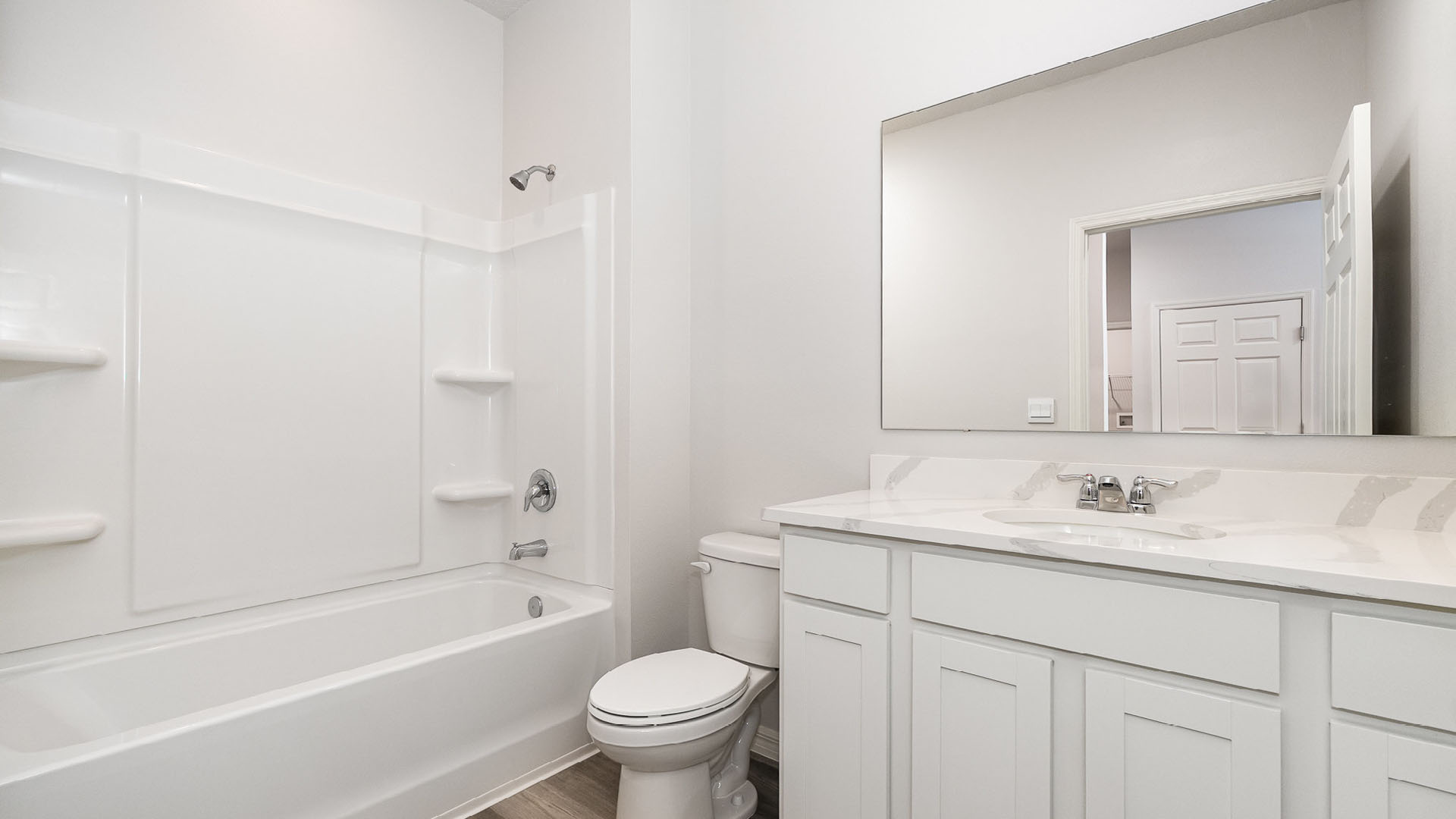 16. Bright and modern bathroom featuring a white tub, toilet, and double vanity with a large mirror against neutral walls.