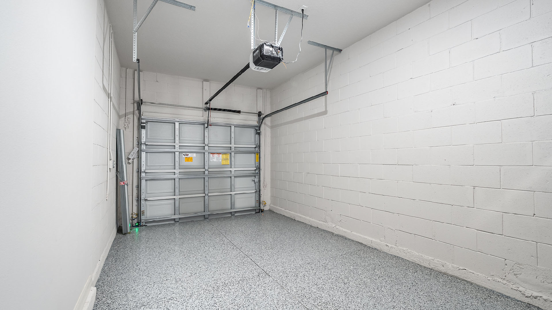 A spacious, 1-car garage with a garage door, and a white cinder block wall.