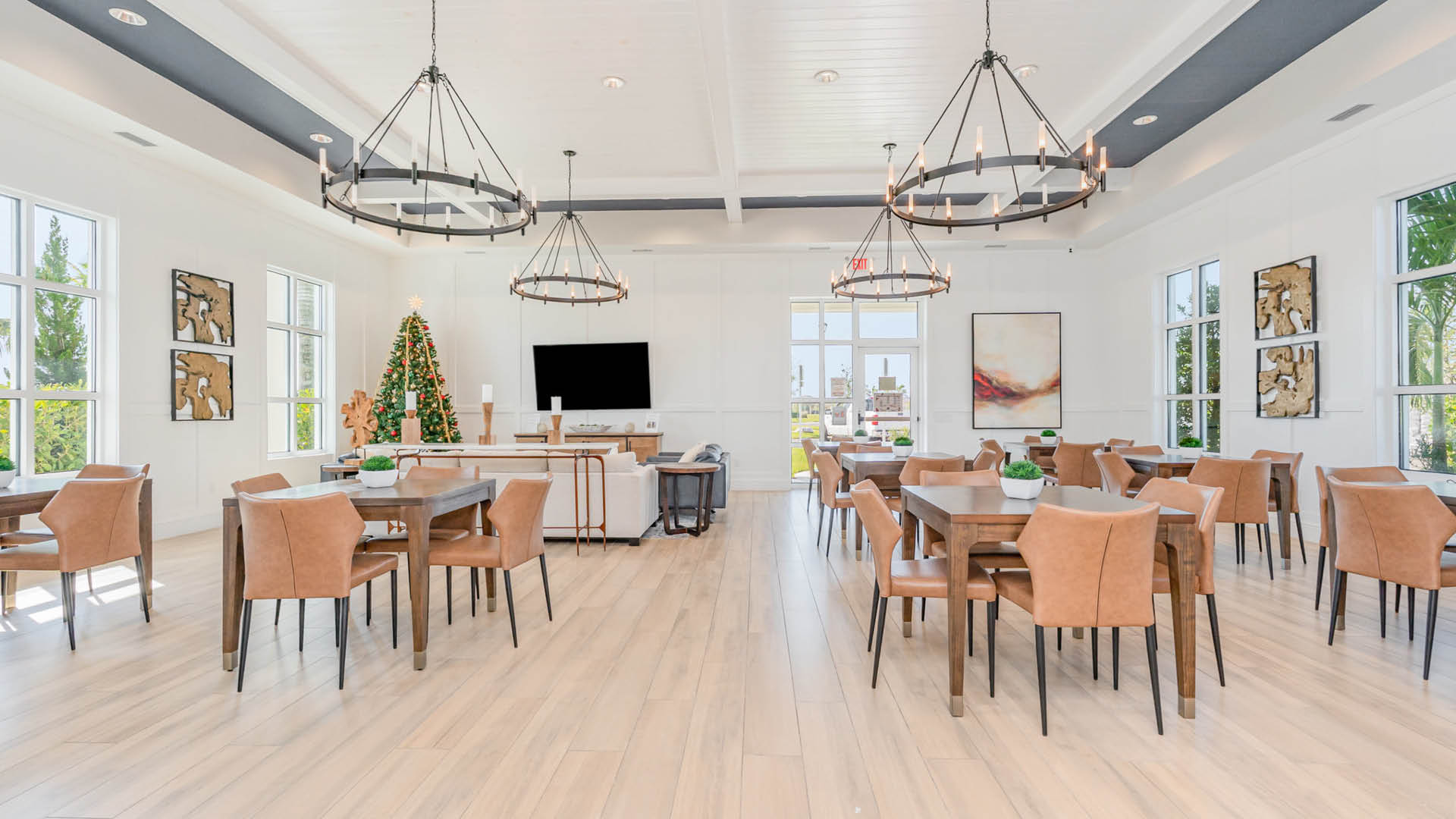 Bright, modern dining area with light wood floors, tan leather chairs, and wooden tables.