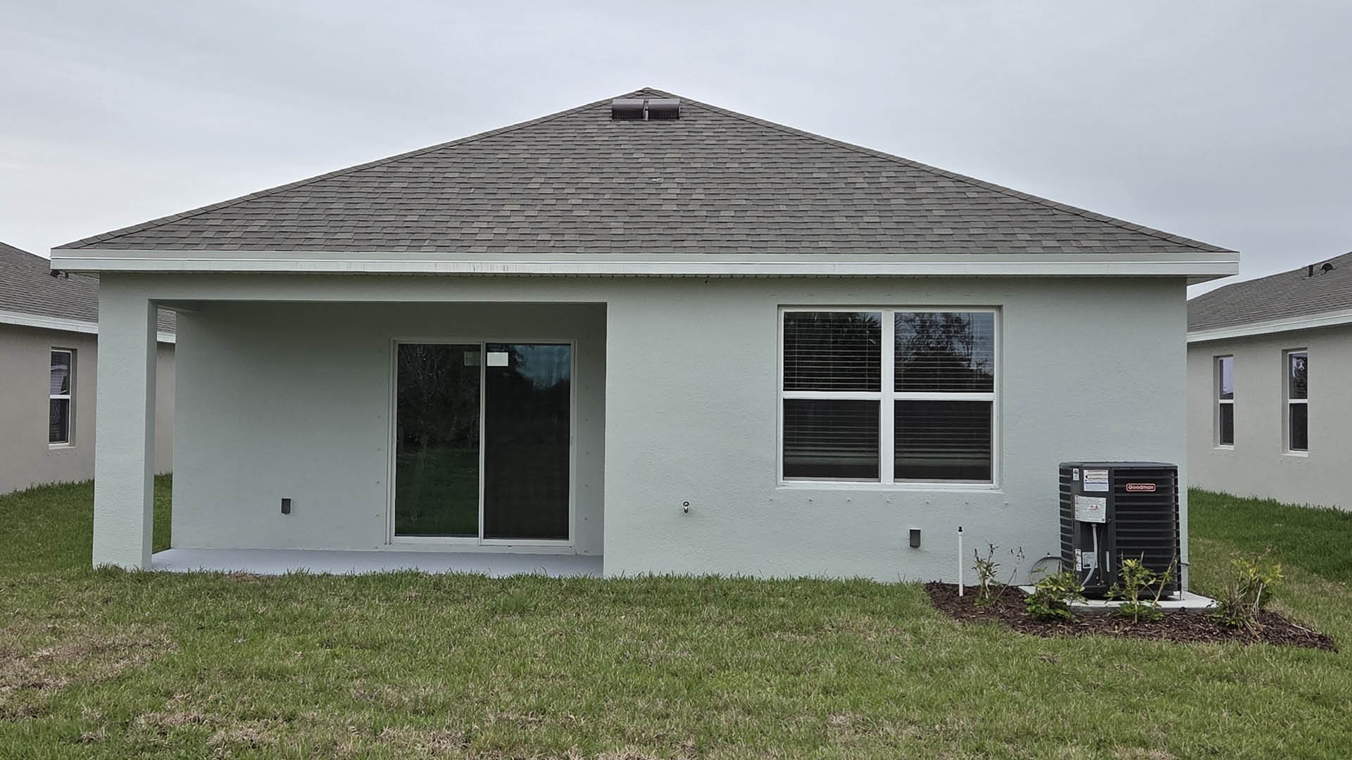 An exterior photo showing a rear view of a modern single-family home with a shingled roof and manicured landscaping.