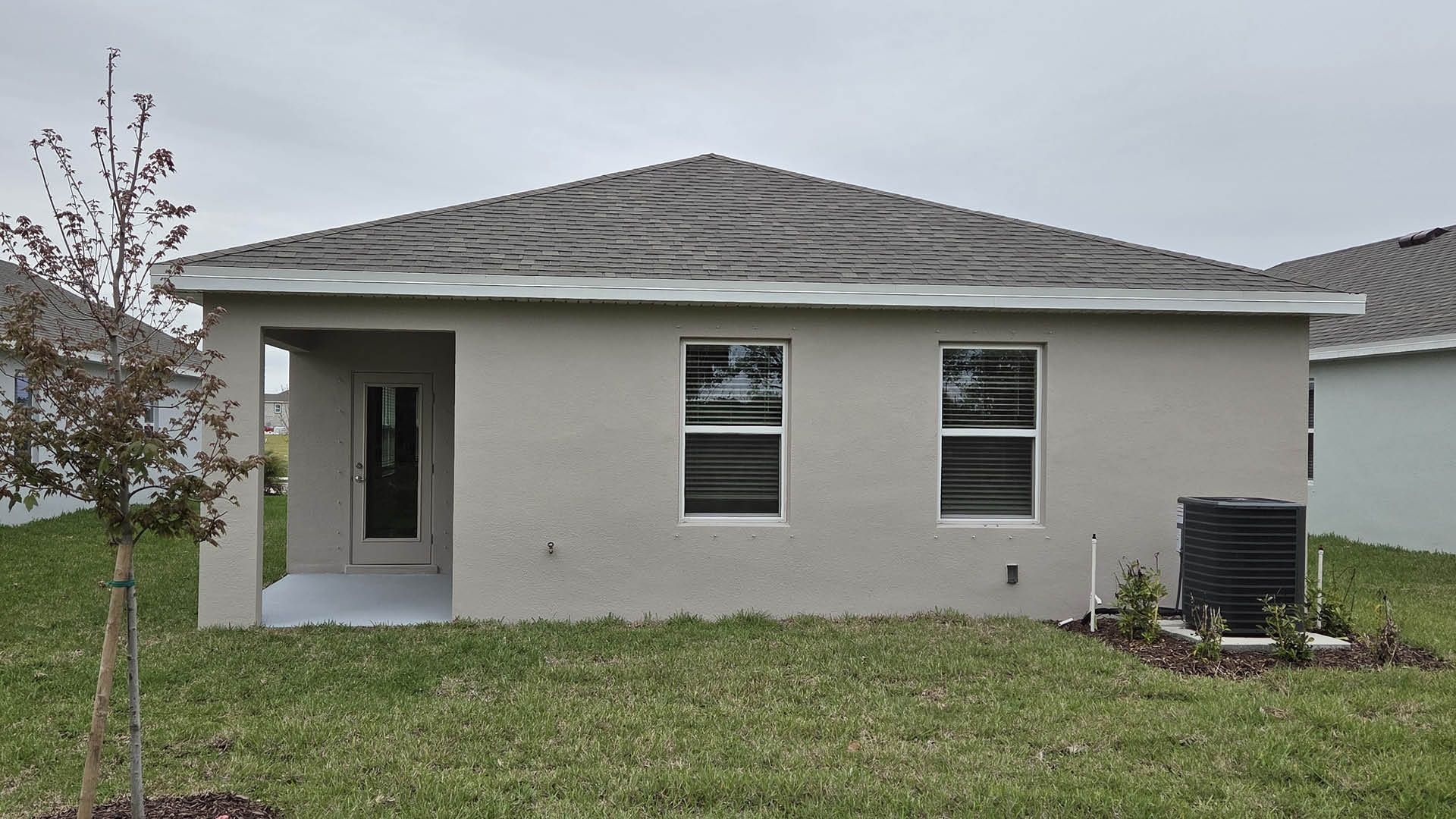 An exterior photo showing a rear view of a modern single-family home with a shingled roof and manicured landscaping.