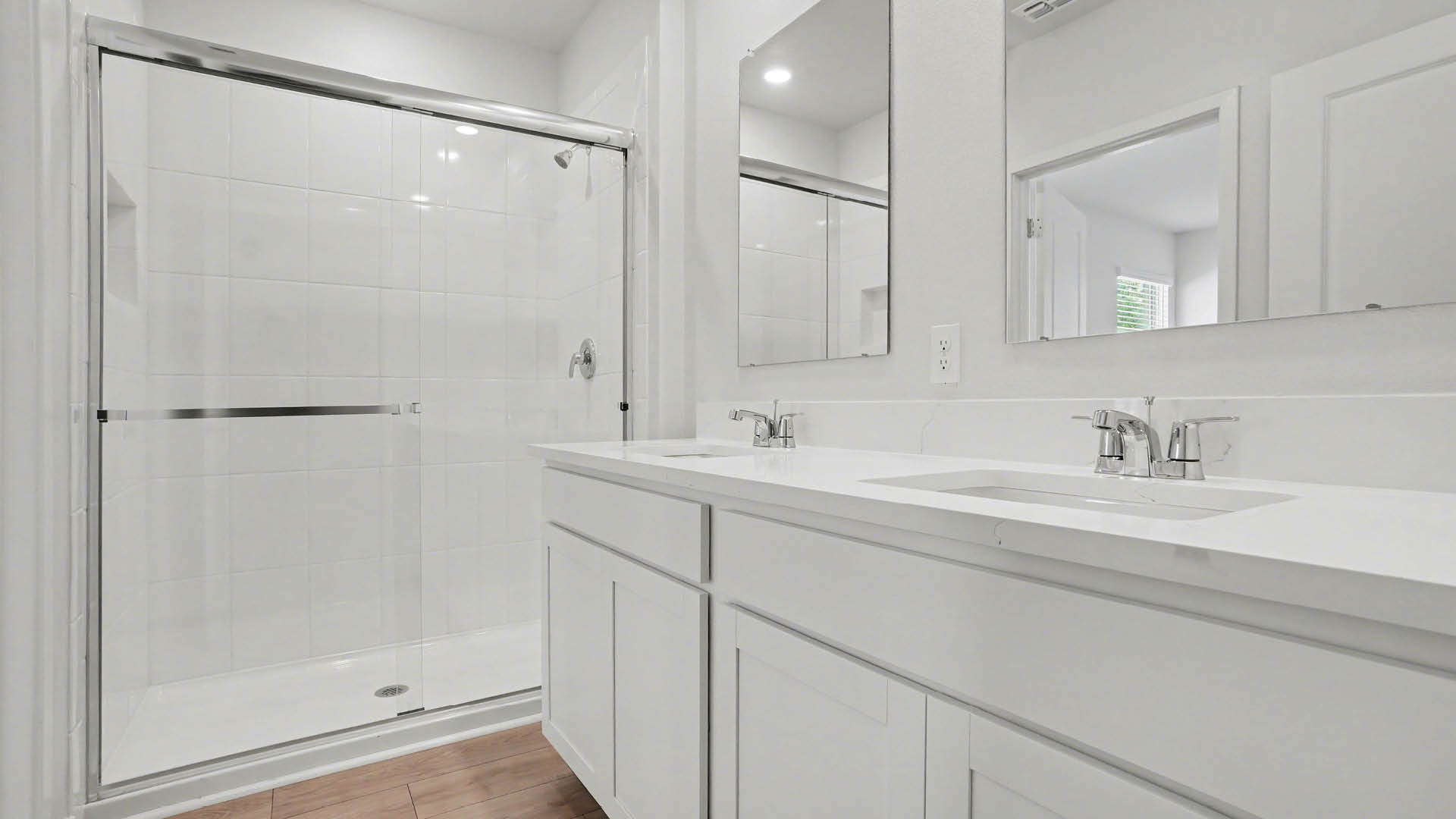 A spacious, modern bathroom featuring a walk-in shower and double sink vanity with quartz countertops.