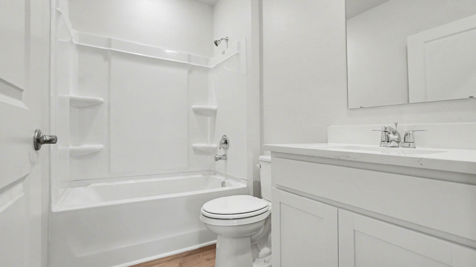 A clean, modern bathroom featuring quartz countertops, a bathtub with a shower, and a large mirror against neutral-colored walls.