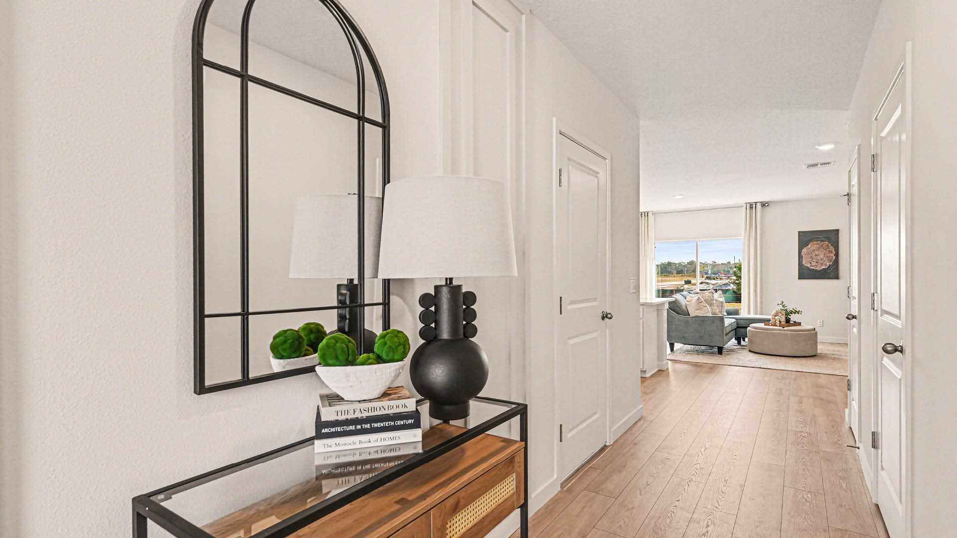 A welcoming entryway with Mohawk® Revwood Select Plank Flooring. The hallway has several doors and leads to a living room with large window further in.