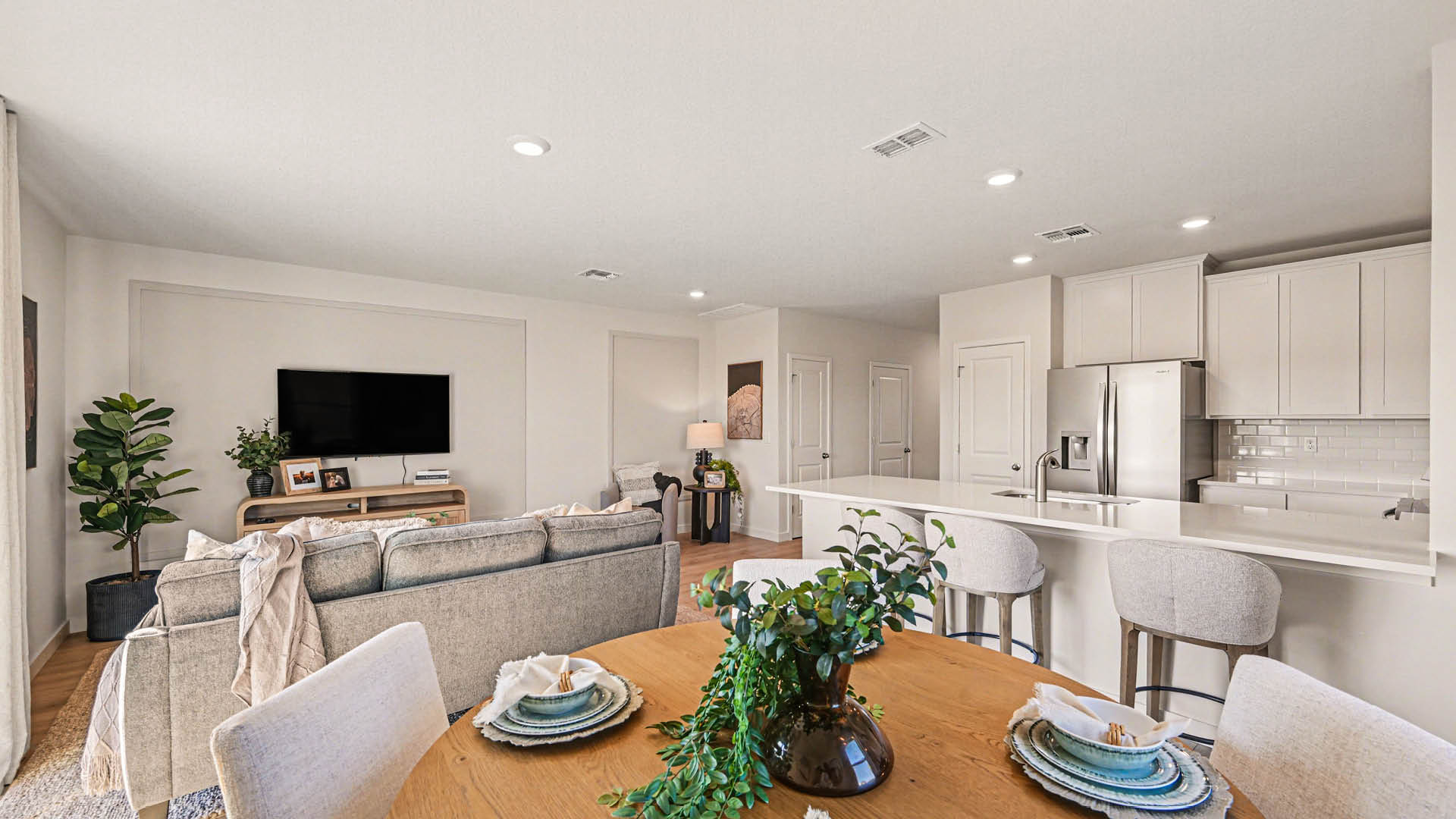 A dining room with access to the living room and kitchen. Natural light is streaming in, highlighting the beautiful white cabinetry.