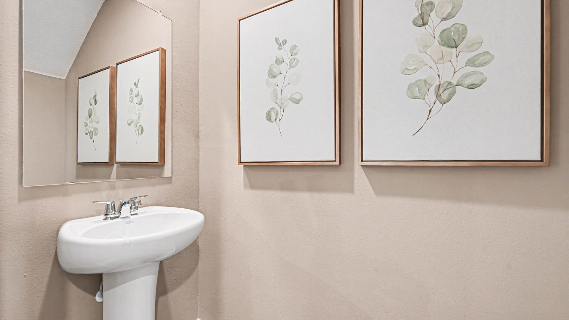 A bathroom with a sink and three pictures on the wall.