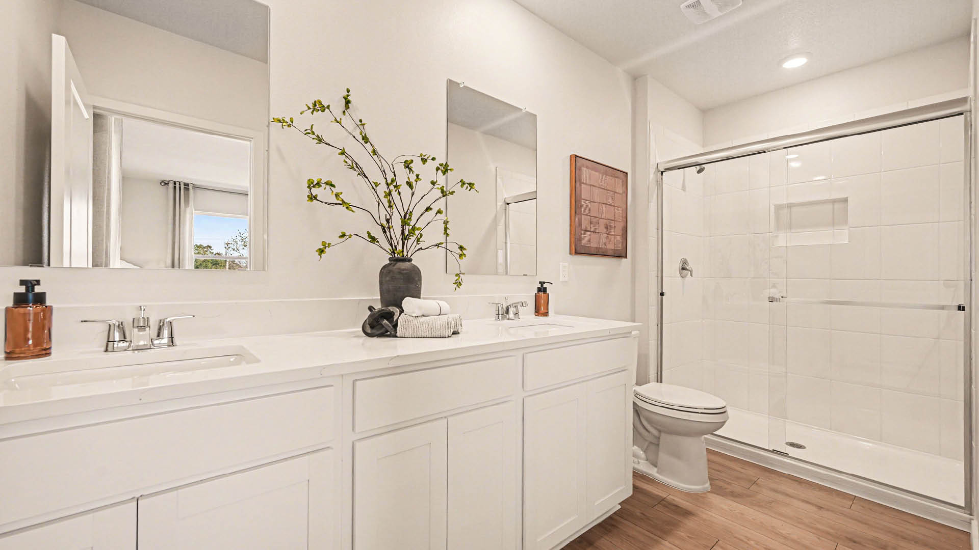 Spacious modern bathroom featuring a glass, walk-in shower, double sink vanity, and bright lighting.