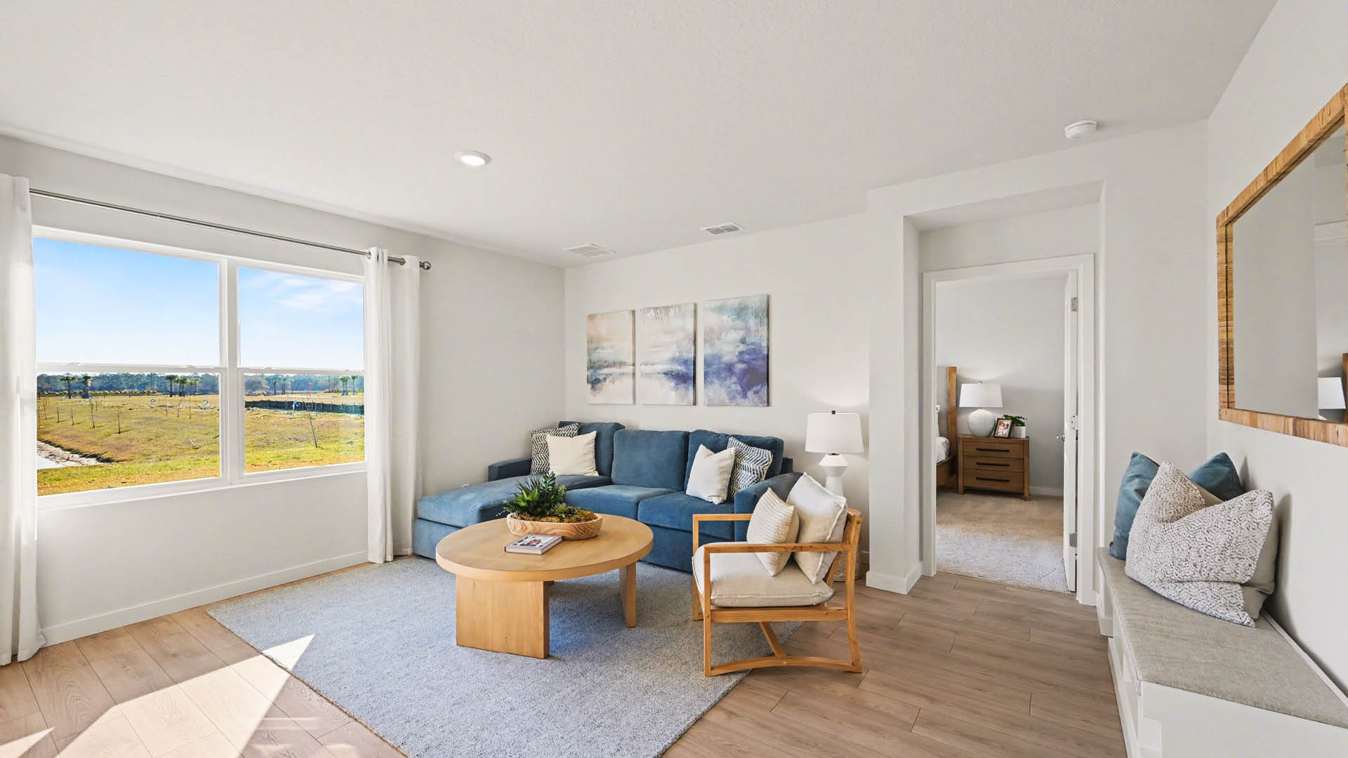 A spacious living room with large windows, and minimalistic walls, allowing natural light to enter.