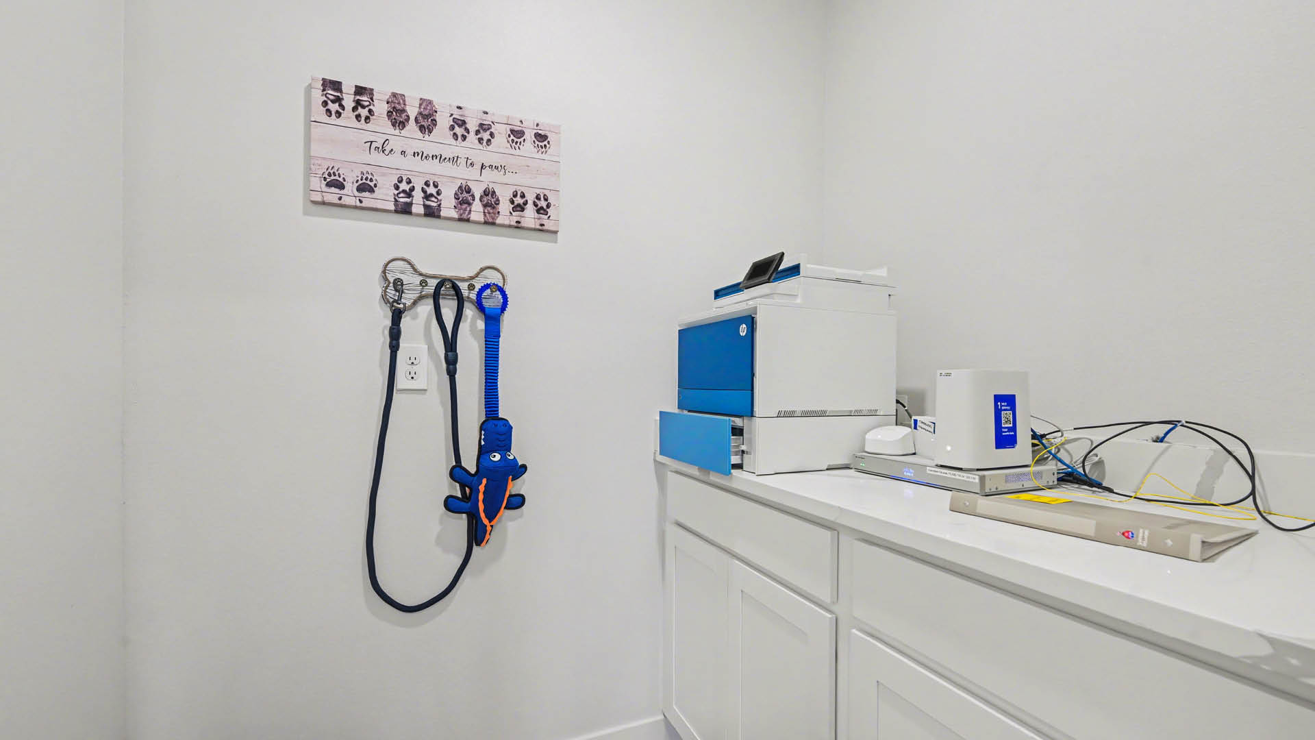 A white room for utilities with a desk and a printer.