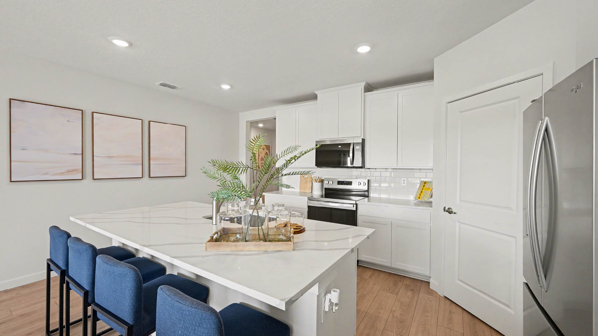 Bright modern kitchen featuring stainless steel appliances, sleek white cabinetry, and a center island with seating.