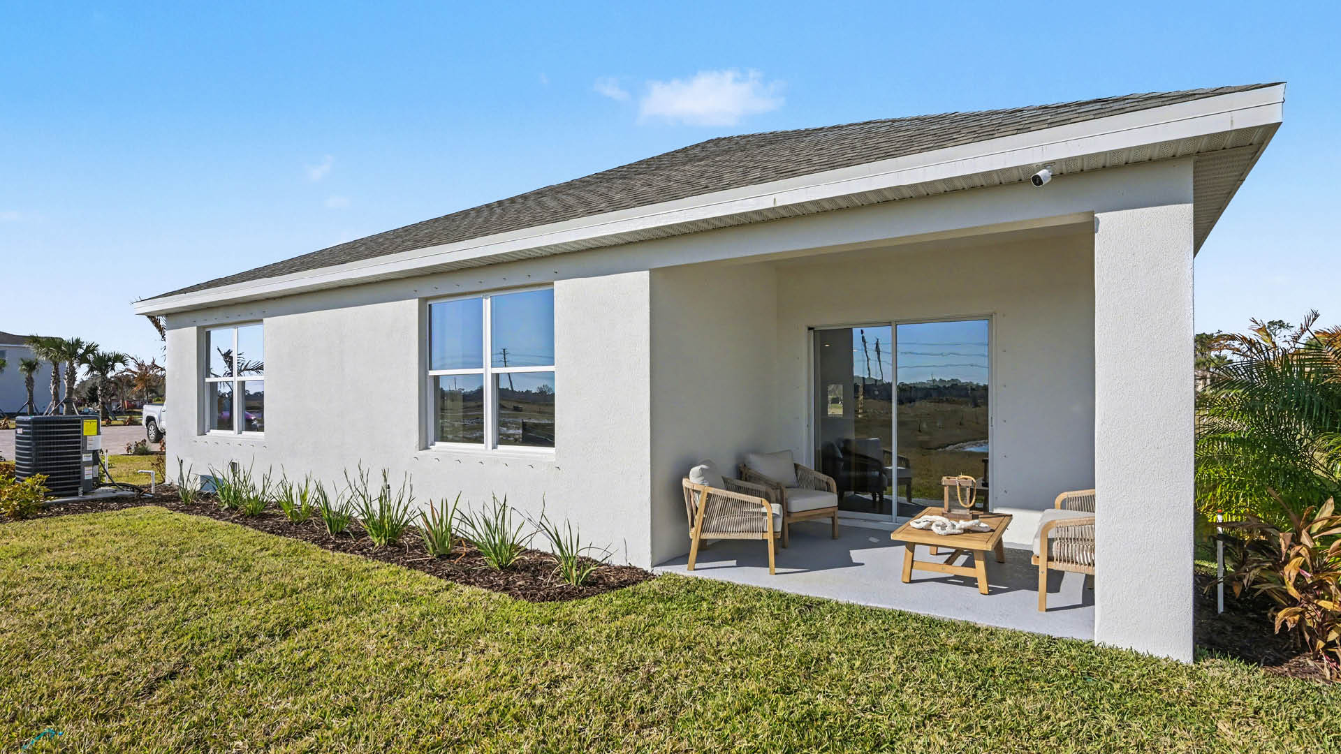 Rear view of a house featuring a white stucco exterior, sliding glass door, and a covered patio.