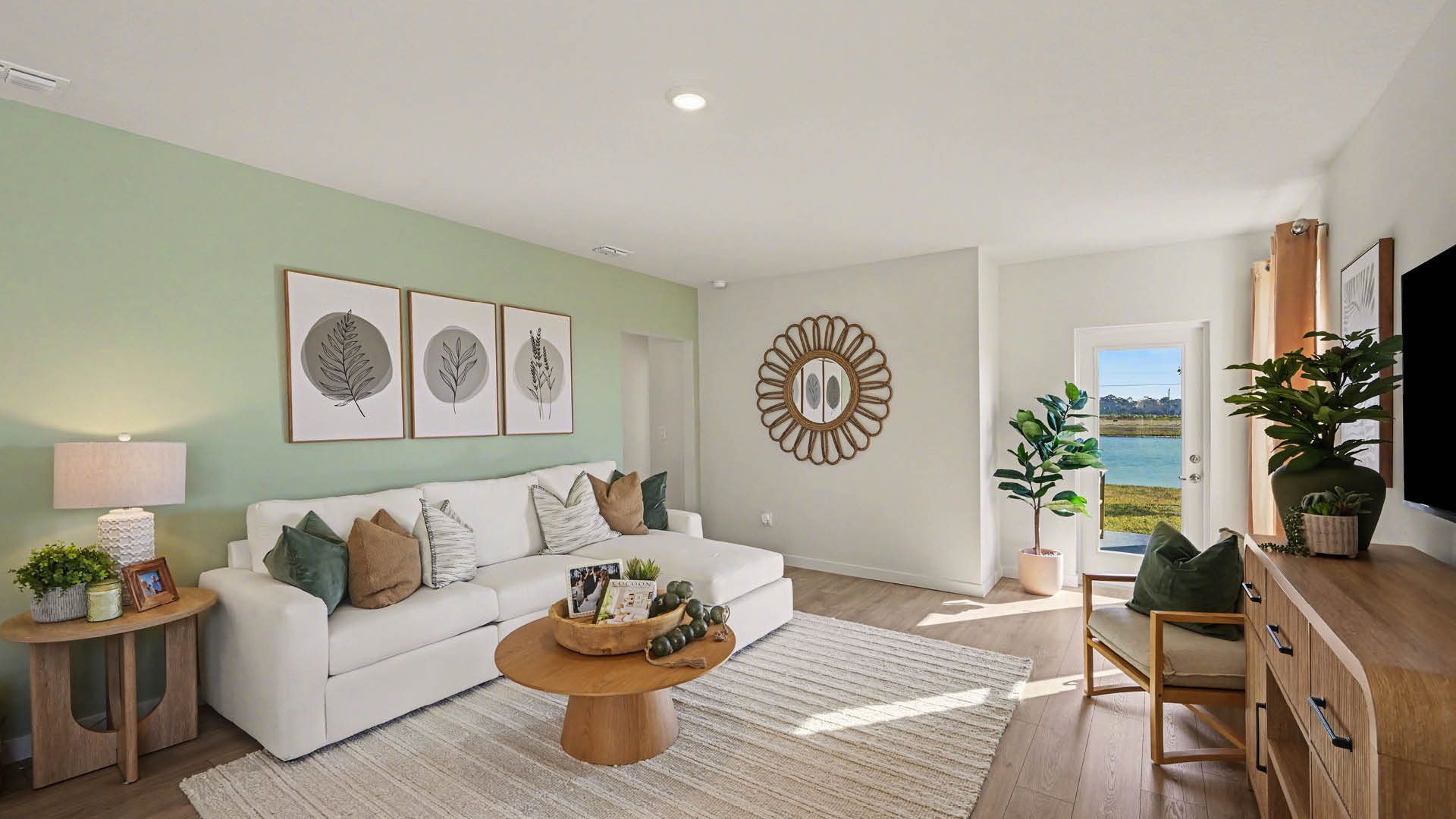 A spacious living room with a door with a glass window. Bright, natural light filters in along the Mohawk® Revwood Select Plank Flooring.