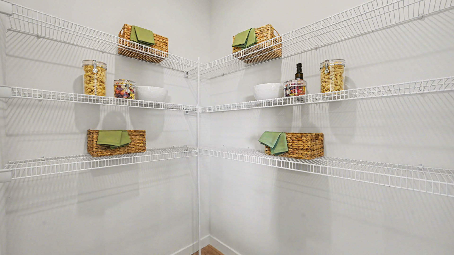 A spacious kitchen pantry featuring multiple white wire shelves against a light-colored wall.